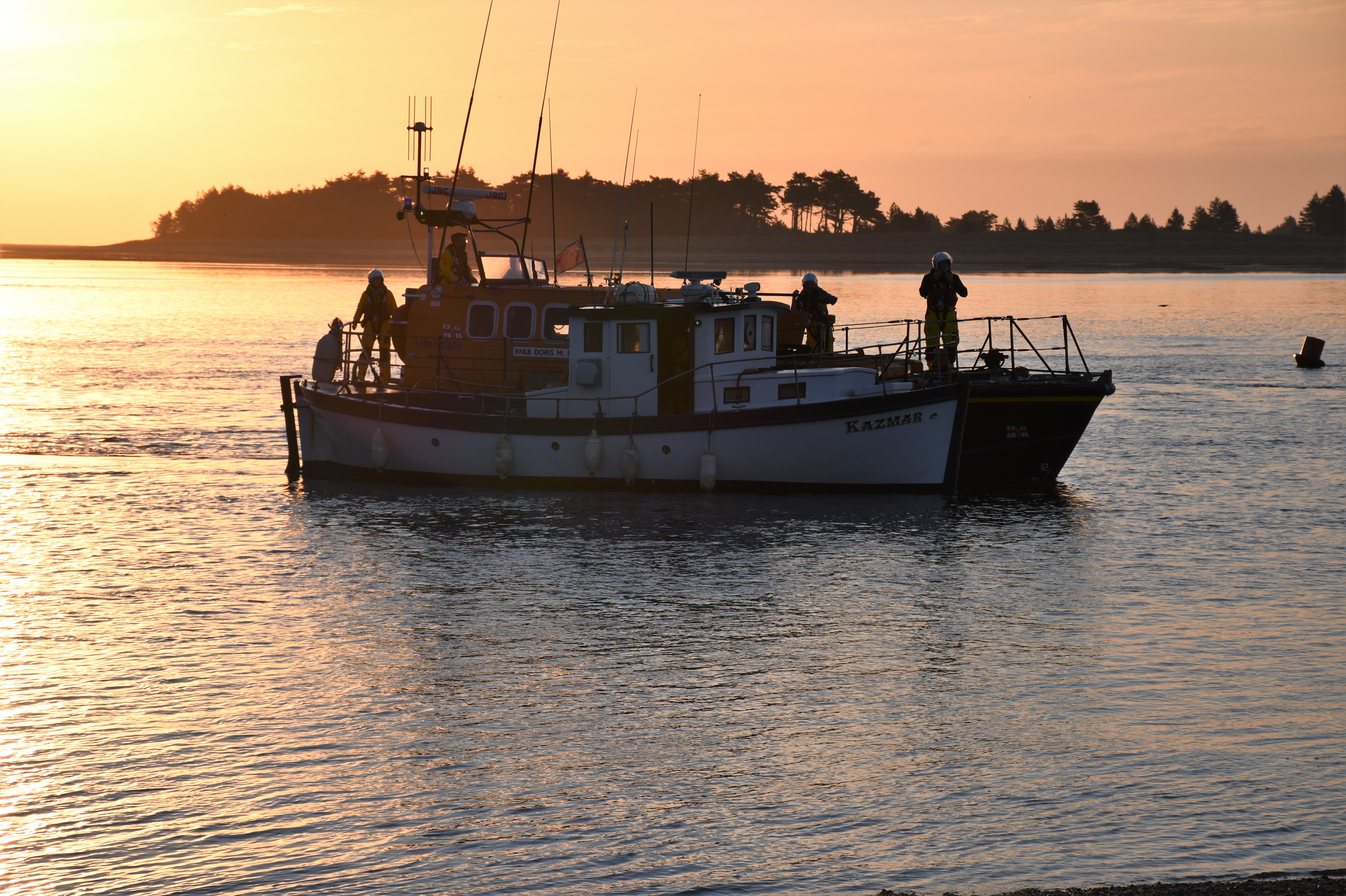 RNLI Wells all-weather lifeboat towing fishing vessel as the sun comes up