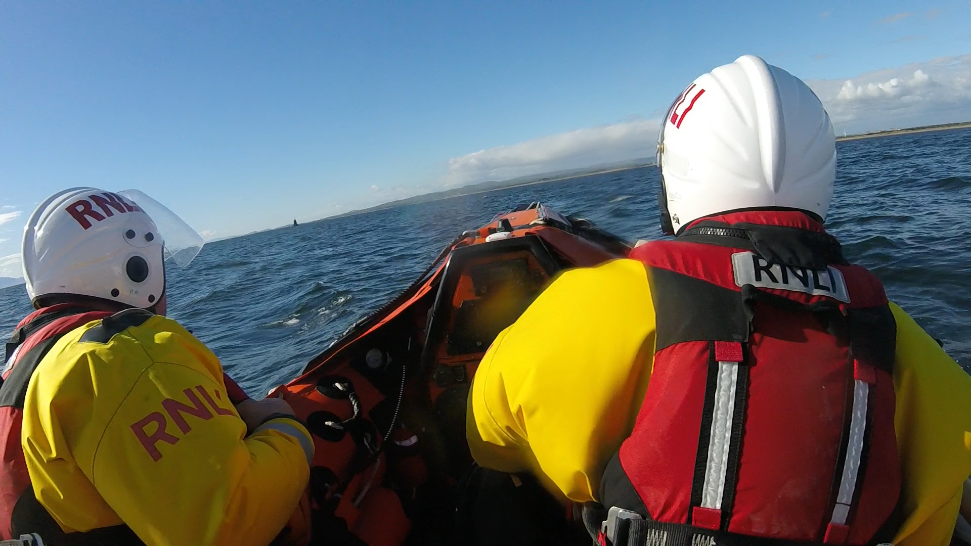 2 crewmembers in drysuits and helmets aboard the D class inshore lifeboat at sea heading for Irvine