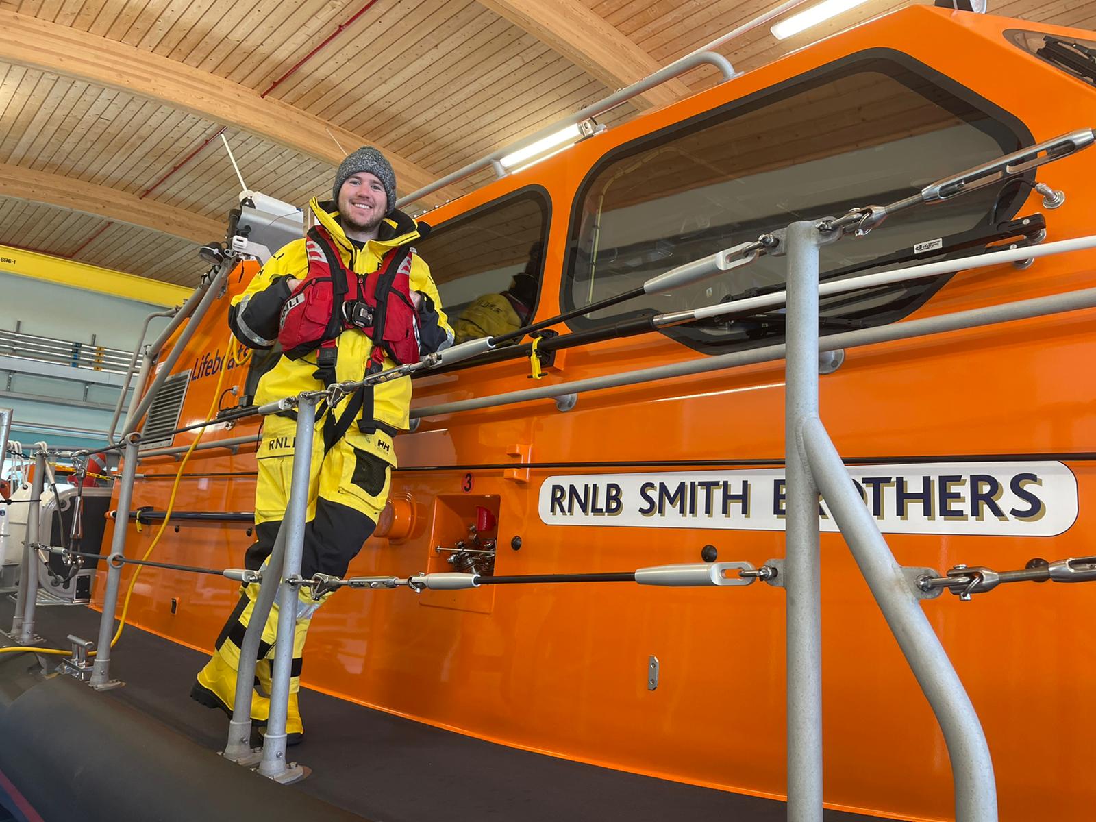 Tomos Moore standing on RNLI Pwllheli's Shannon lifeboat
