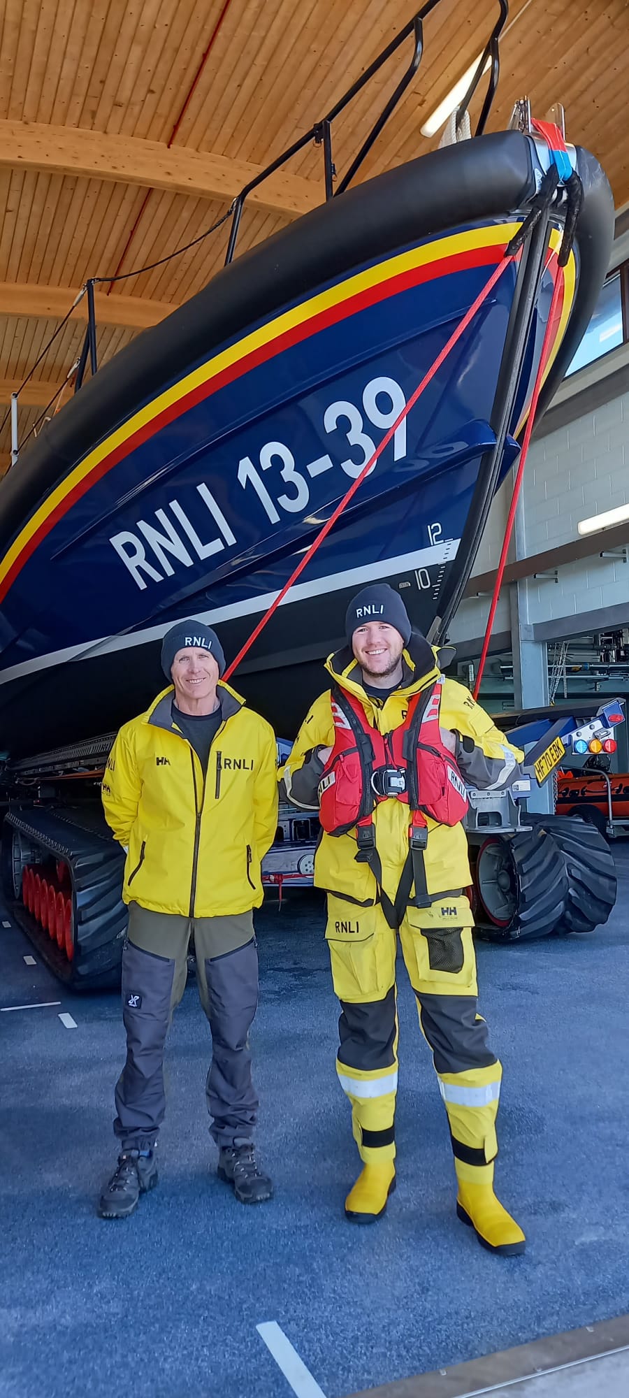 Clive, standing on the left and Tomos Moore standing in front of the Shannon lifeboat inside RNLI Pwllheli boathouse