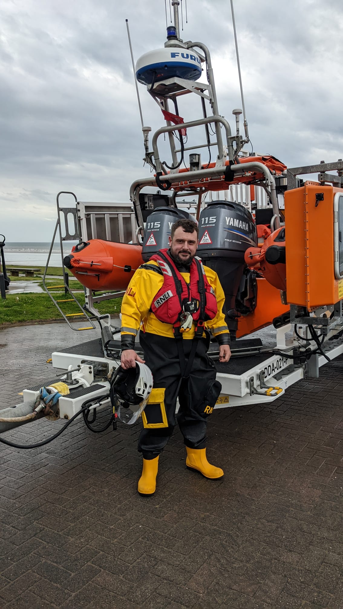 Boat crew volunteer standing in front of Atlantic class inshore lifeboat.