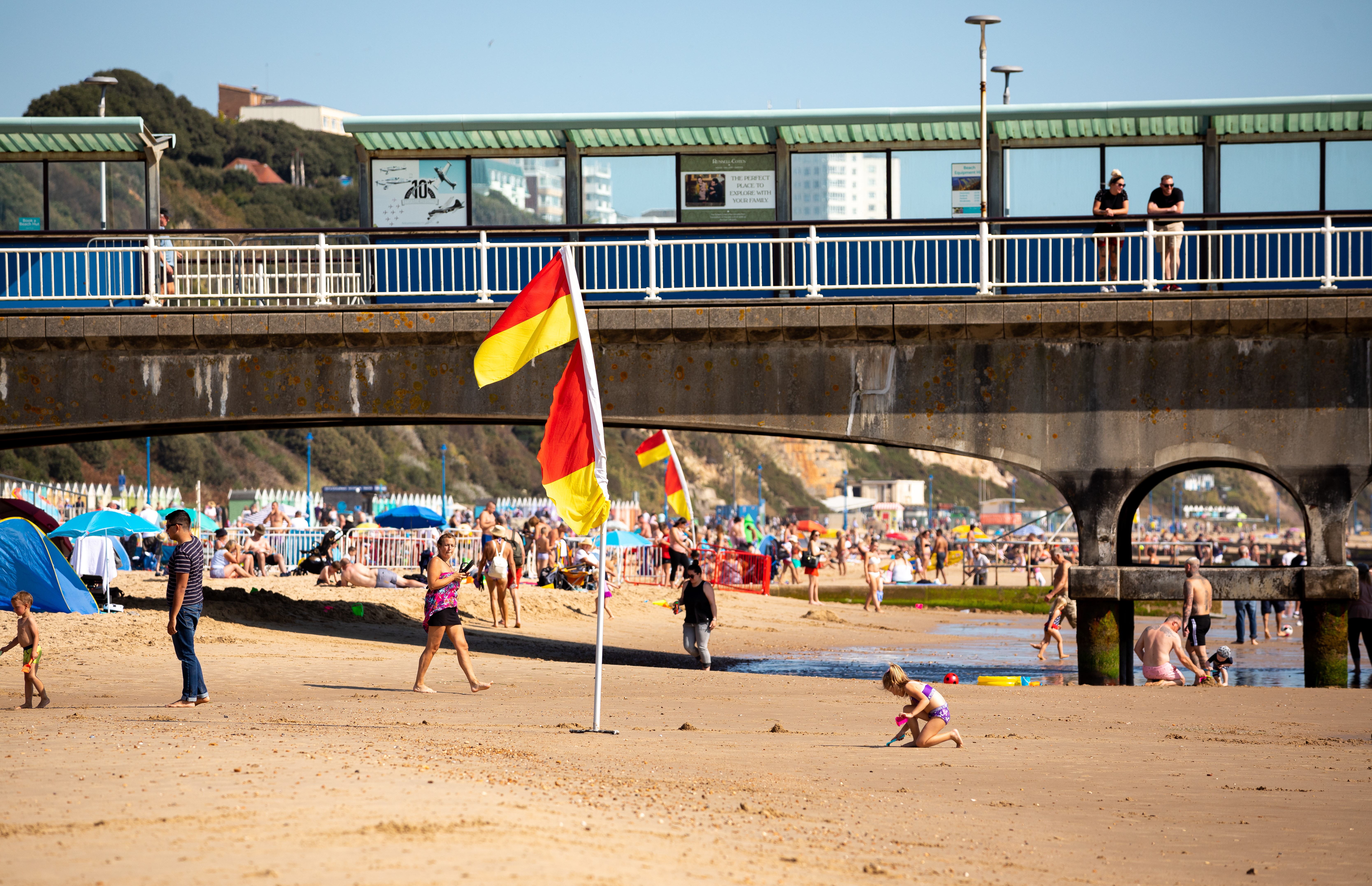 Red and yellow lifeguard flags at Bournemouth beach on a busy, sunny summer day