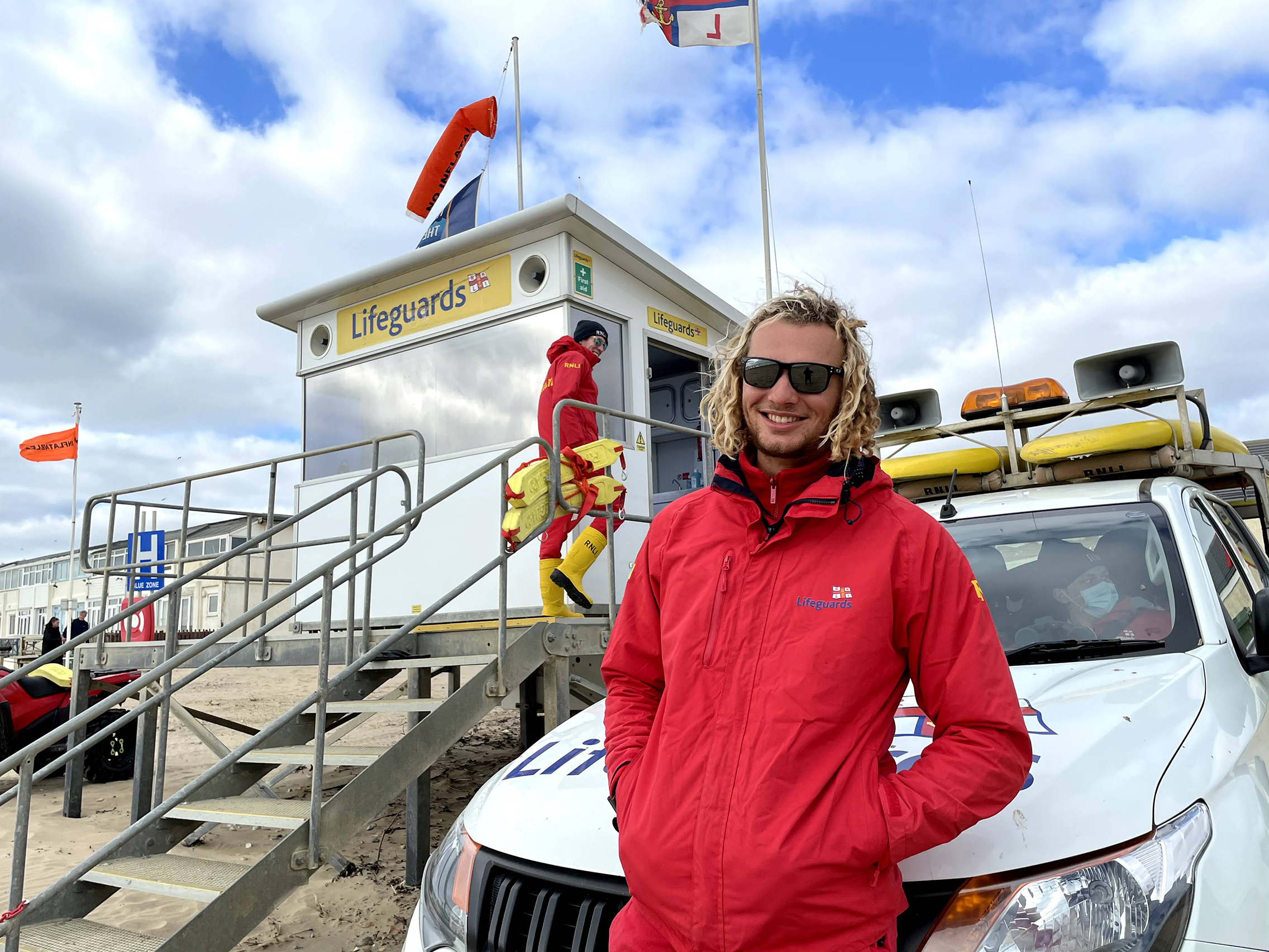 Two RNLI Lifeguards on Camber Sands beach near the lifeguarding hut