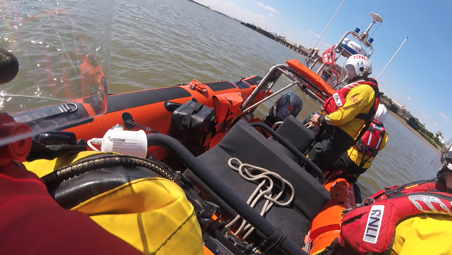 A photo of the Atlantic 85's stern with crew onboard and the hovercraft in tow in the distance