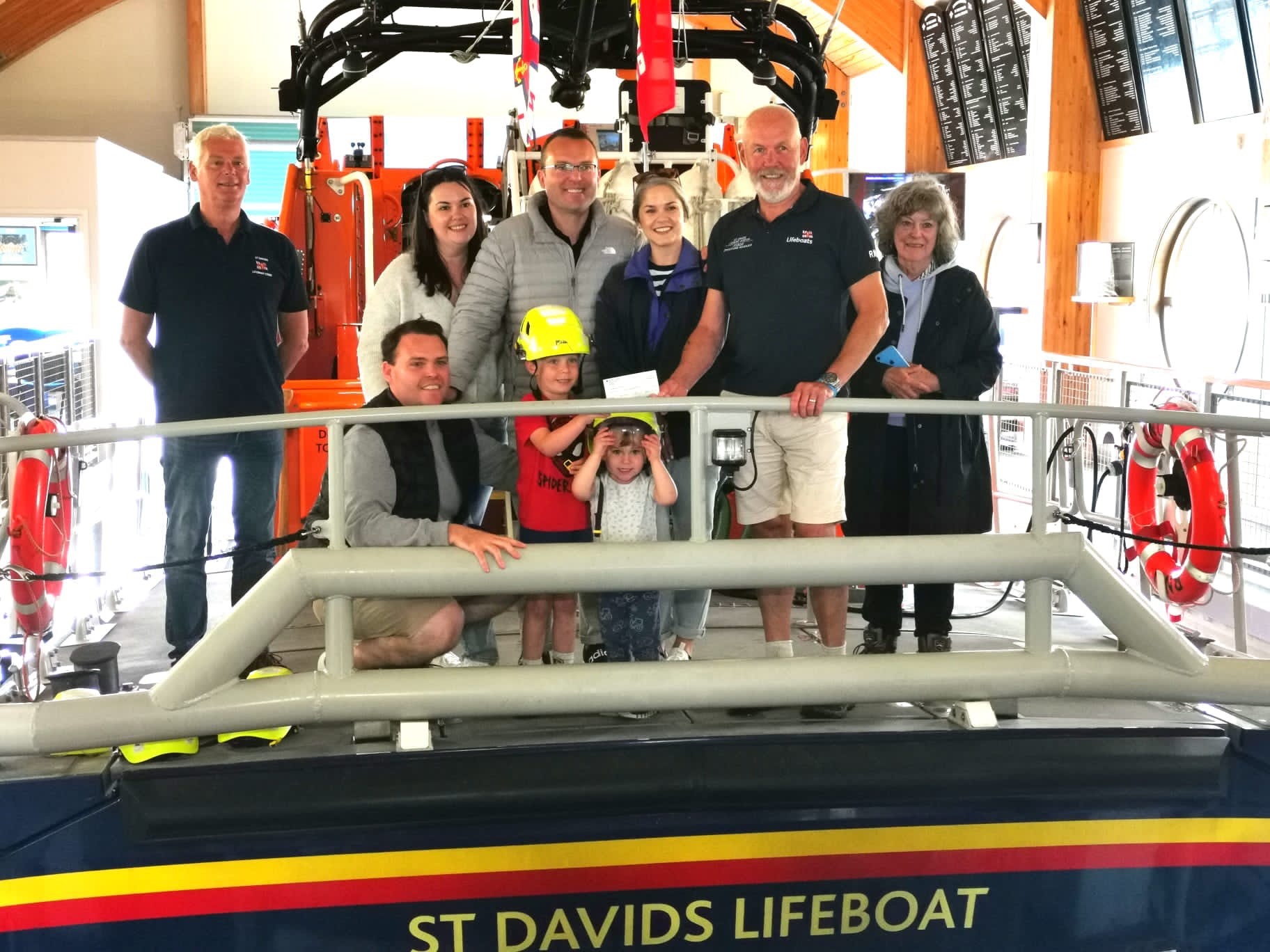 Deputy coxswain Robin Copley and Lifeboat Operations Manager John Williams receiving the cheque from Mollie Thomas' great grandchildren Henry and Teddy