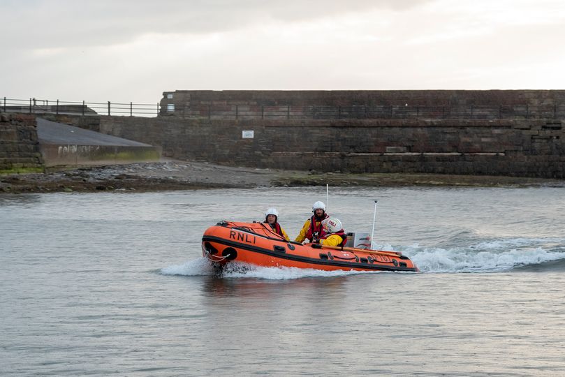 Workington RNLI's inshore rescue boat the John F Mortimer with three crew wearing white helmets in port
