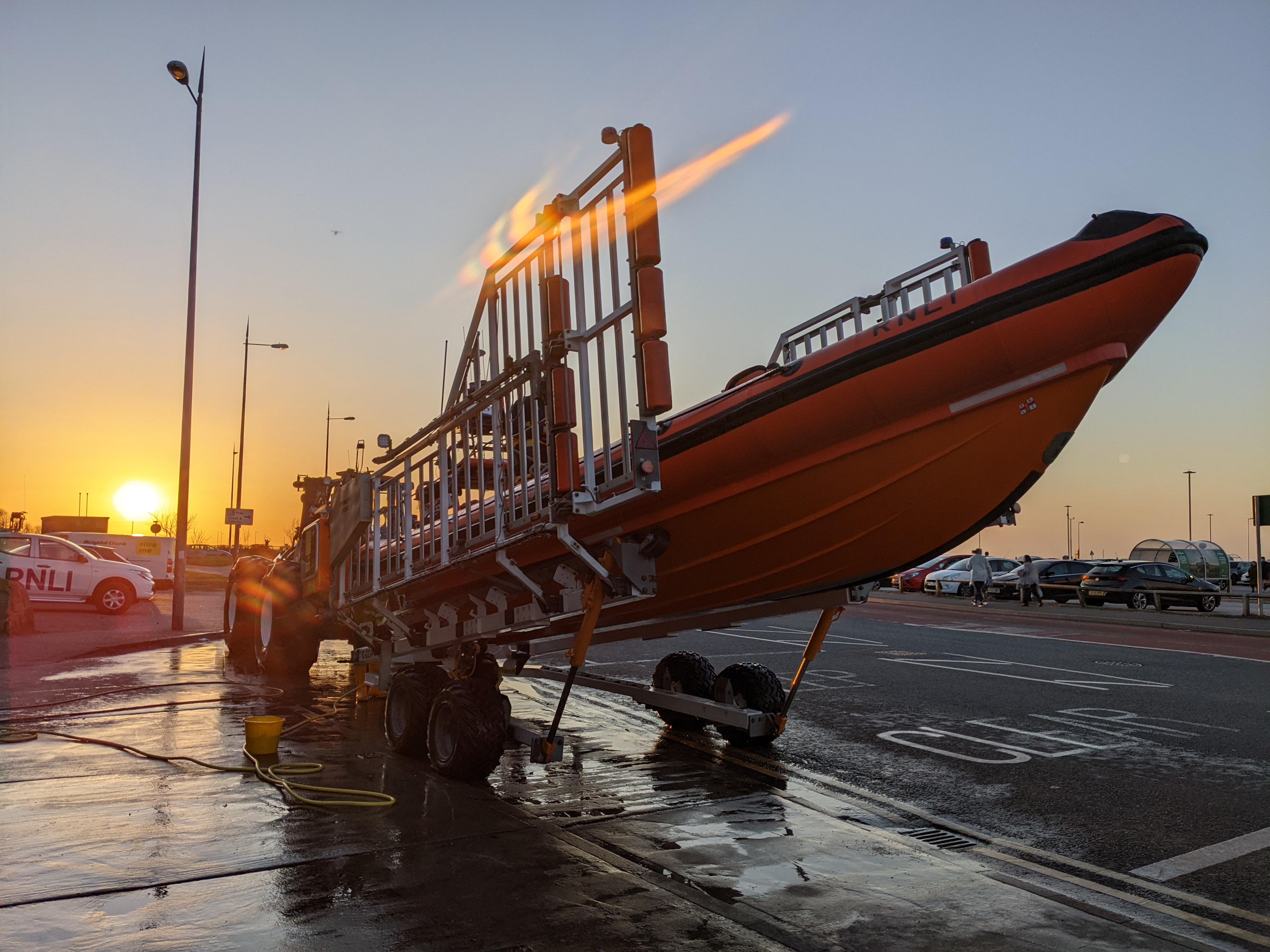 Sunset can be seen in the background. The subject is New Brighton RNLI's Atlantic-85 lifeboat raised on its carriage, being washed and prepared for service once again.
