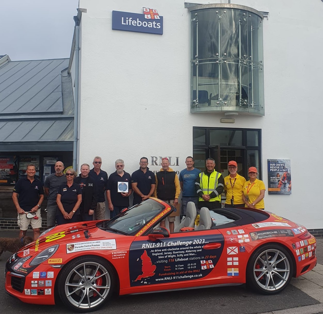 James and Belinda Richardson – in orange caps - and their Porsche 911 ‘Splash’, parked outside the station with crew members from Mudeford RNLI.