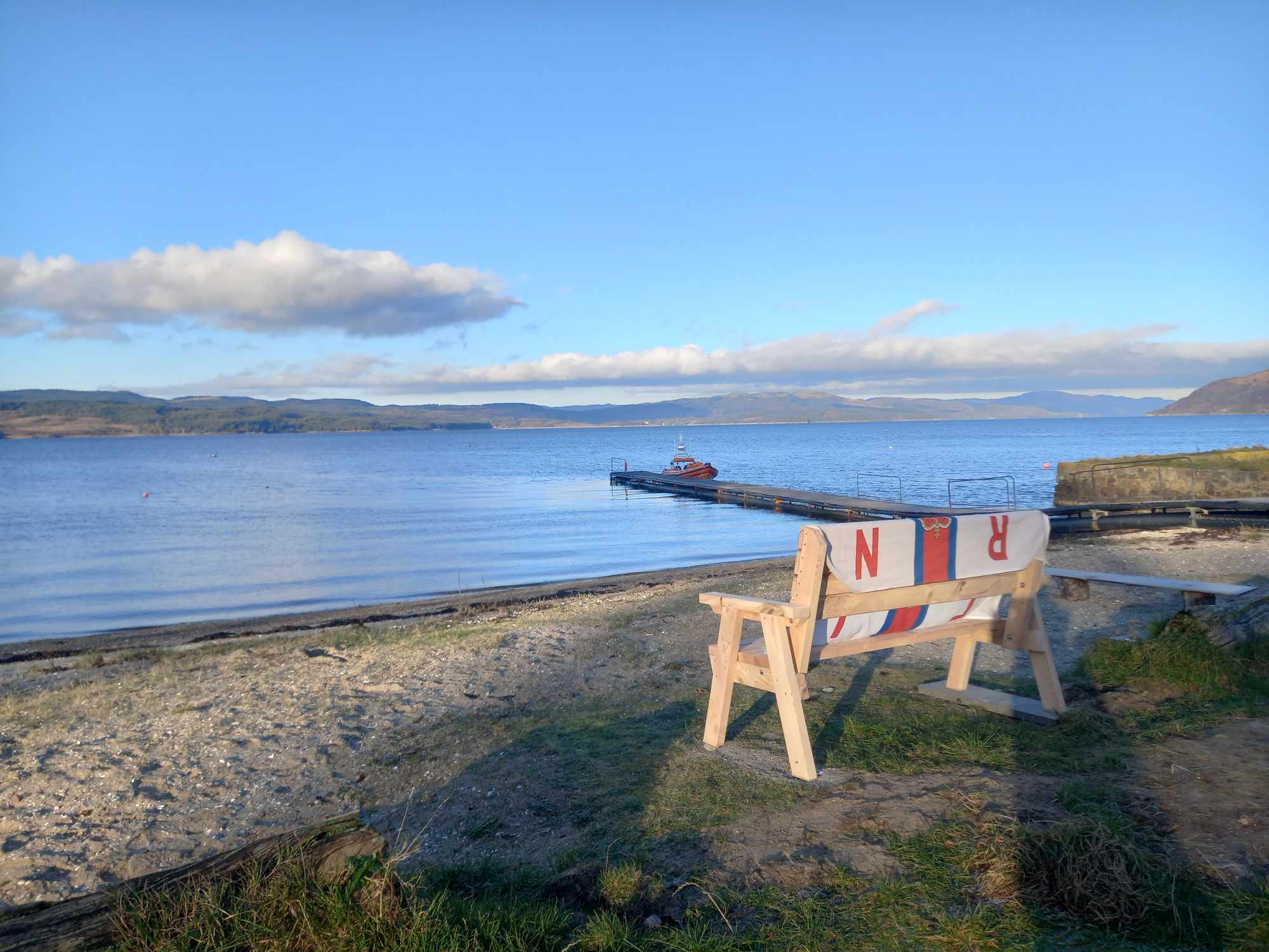 The bench sited by the jetty at Otter Ferry with the inshore lifeboat in the background