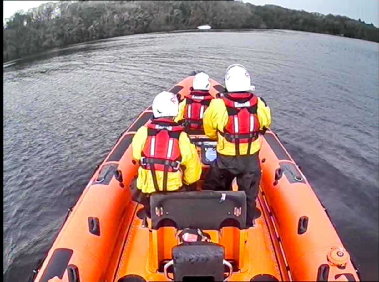 Lifeboat approaching a casualty vessel aground close to shore. View from A-frame behind the 3 RNLI volunteers