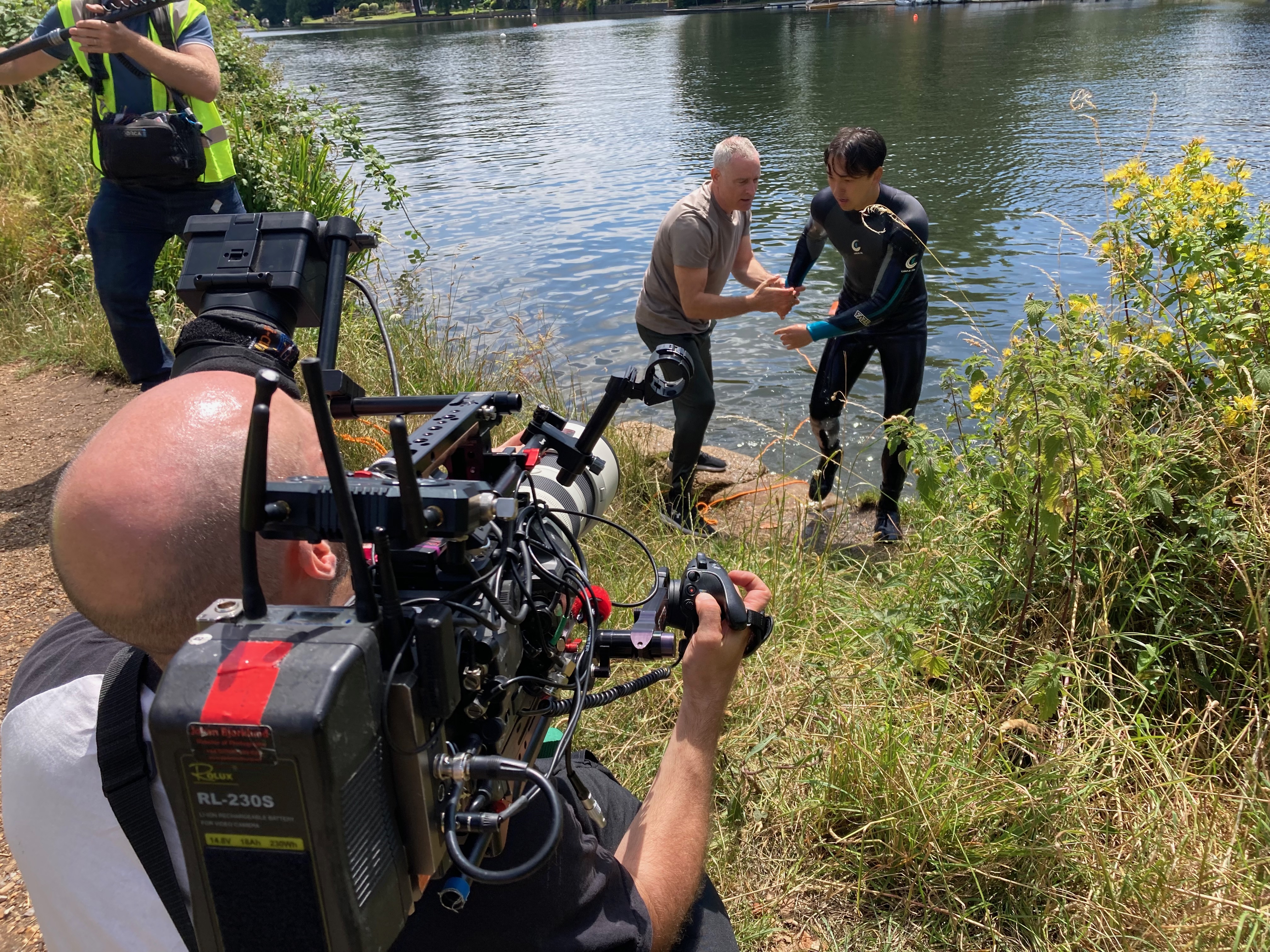 Cameraman shooting member of public helping someone out of the water