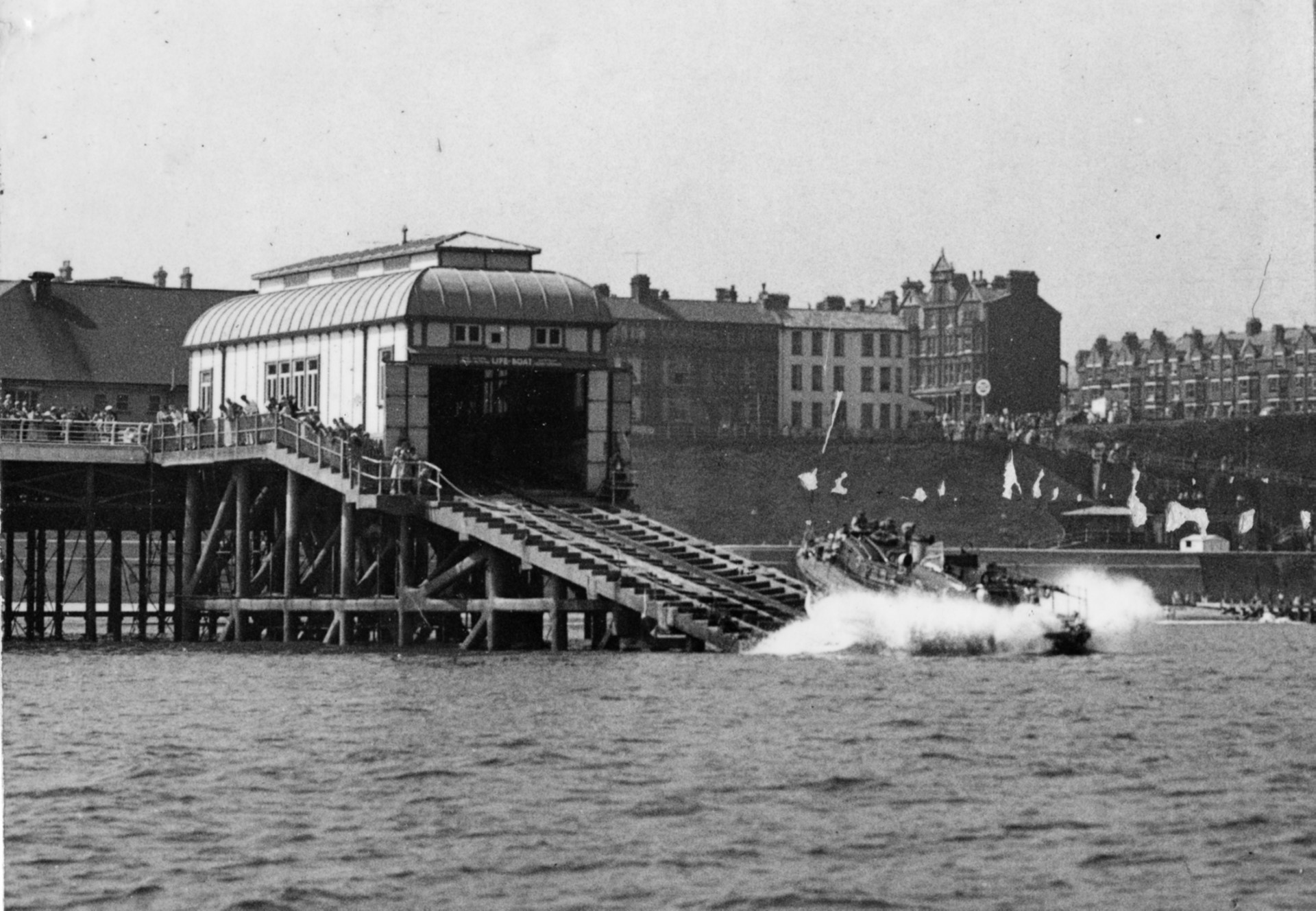 GoPicture shows RNLB Henry Blogg launching down the slipway. In background image of the boathouse showing the small viewing windows on the upper level