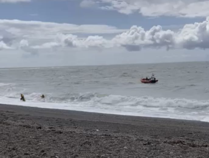 Two RNLI volunteers make their way ashore