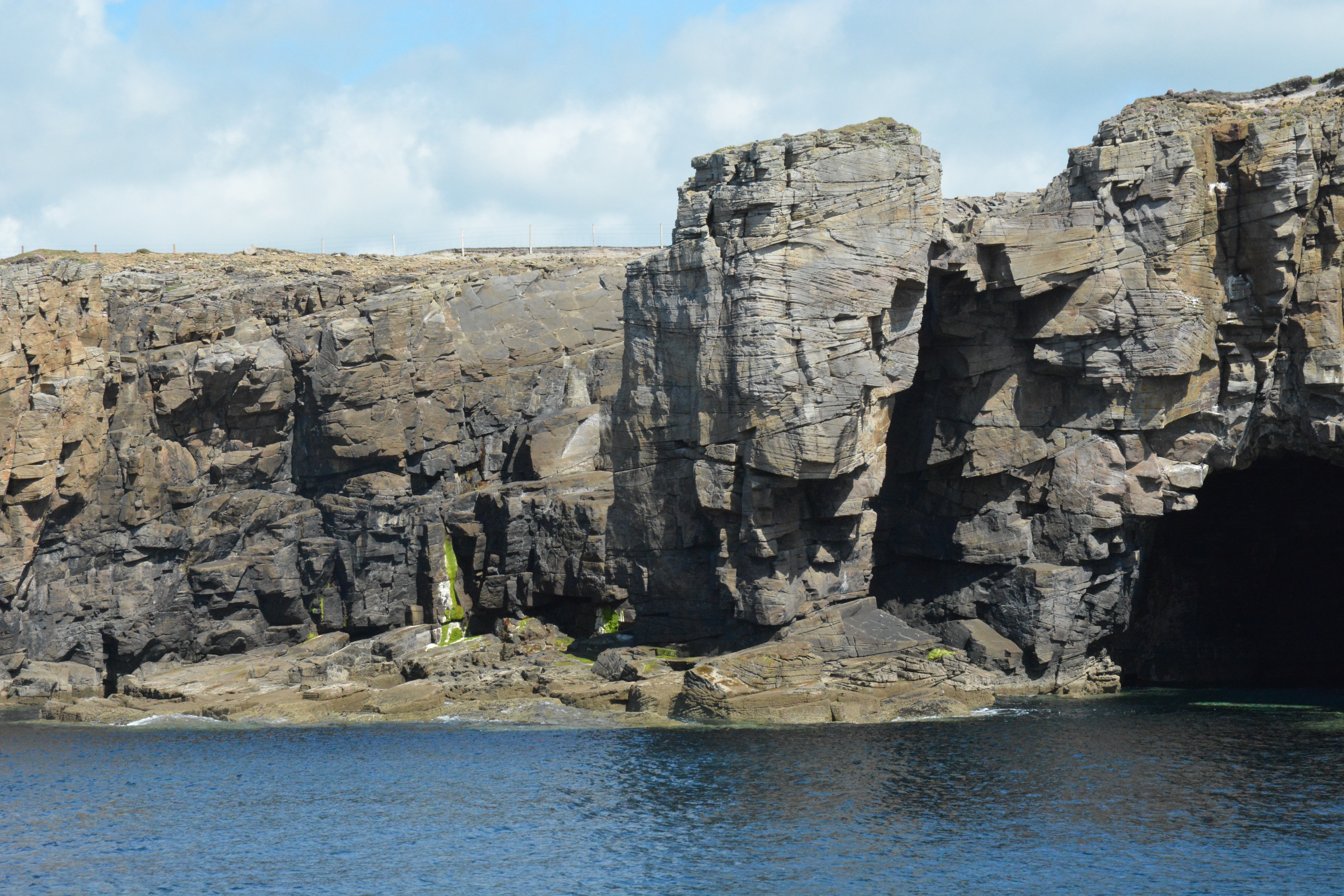 Close up of cliff face with rocks below and calm sea