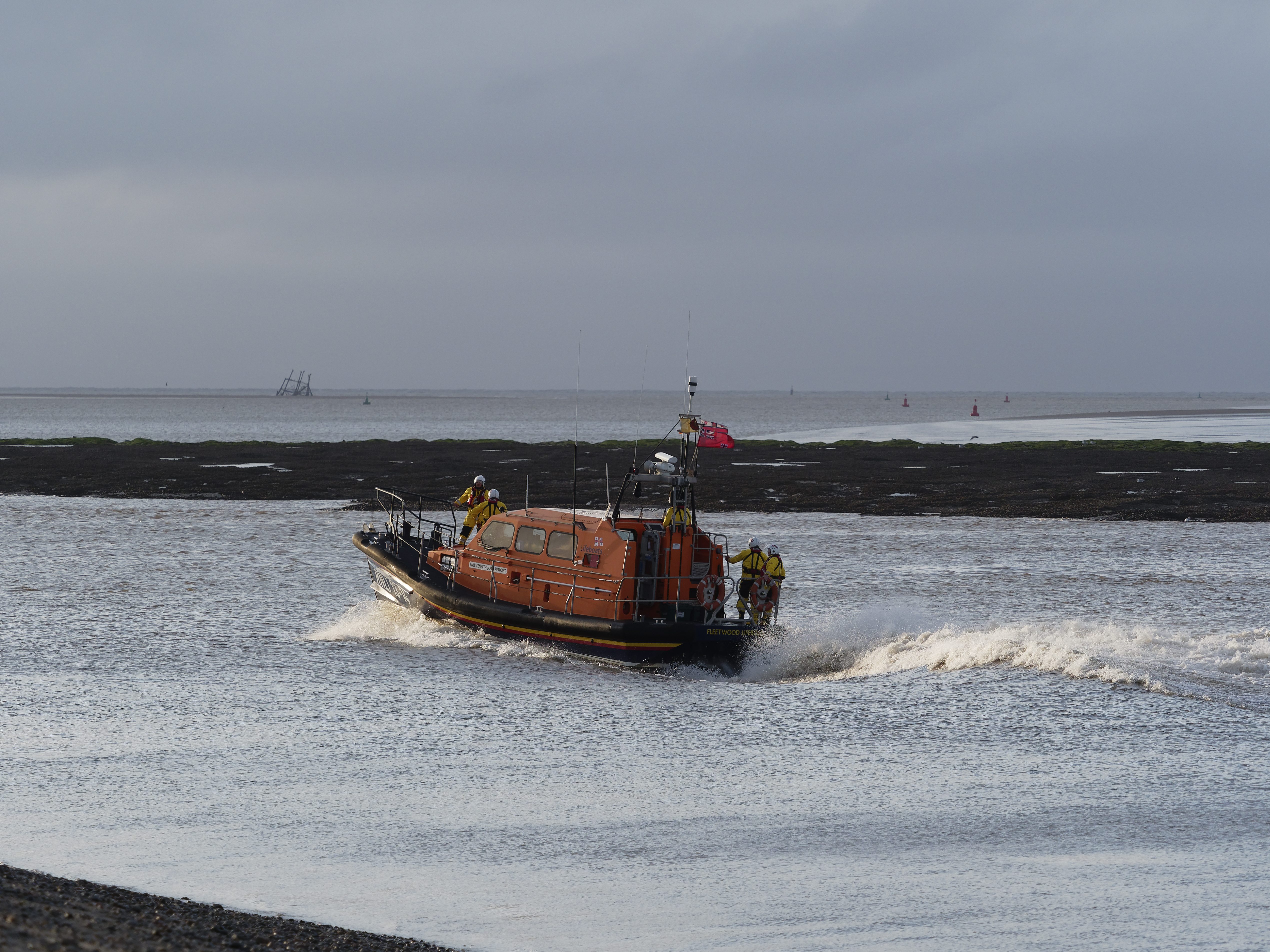 RNLI lifeboat on the water, moving from right to left, leaving a wake in the water