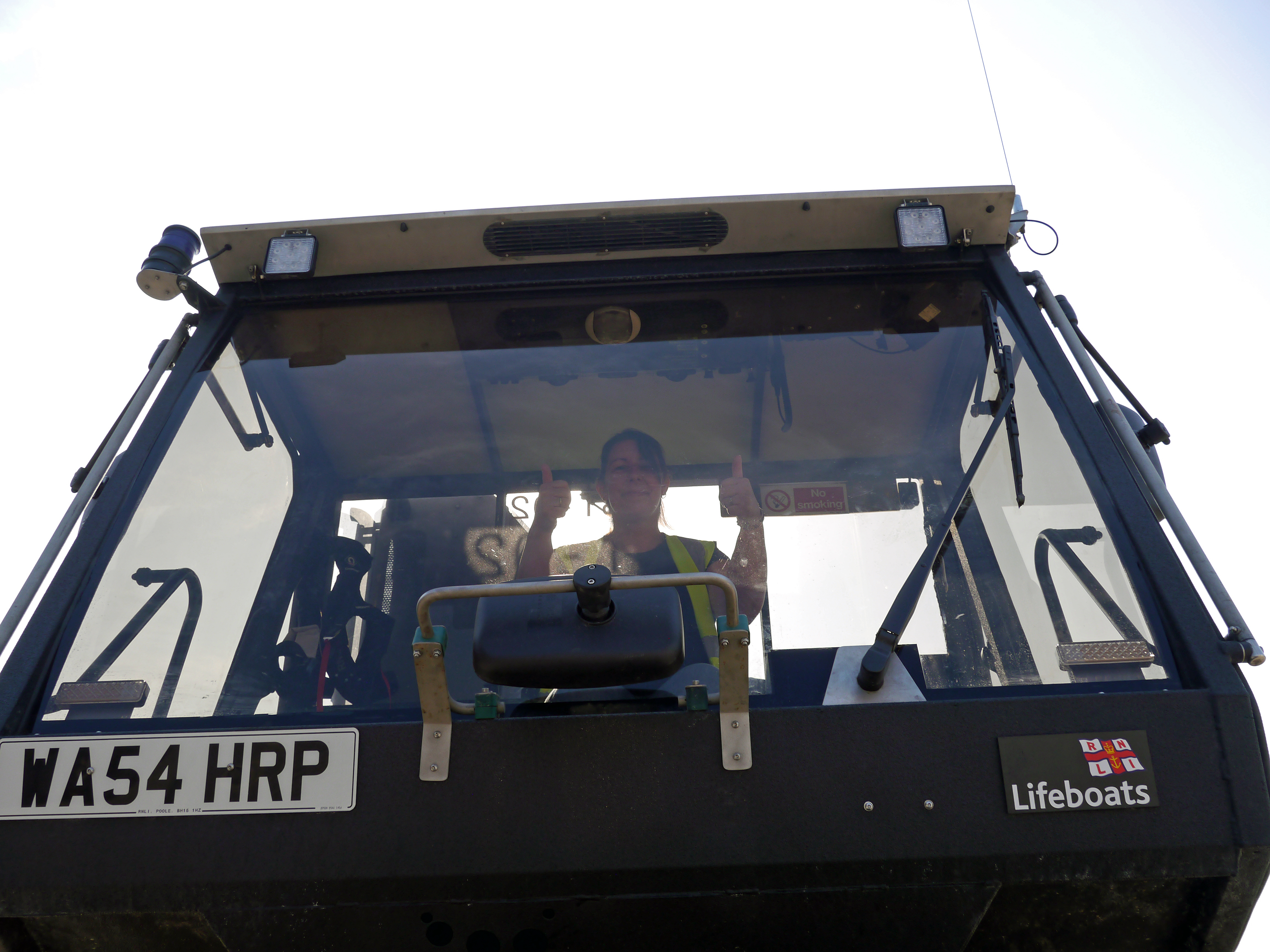 Front view of lifeboat tractor cab with Suzanne sitting inside giving a thumbs up