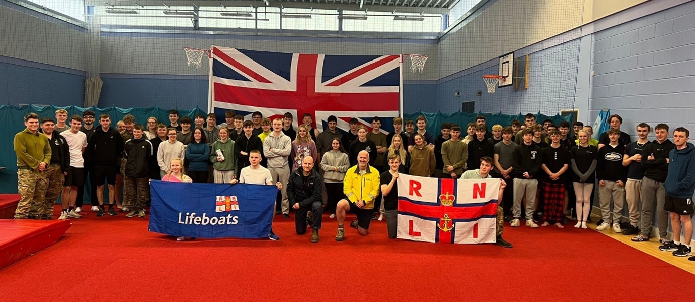 Students standing together holding RNLI flags after completing challenge