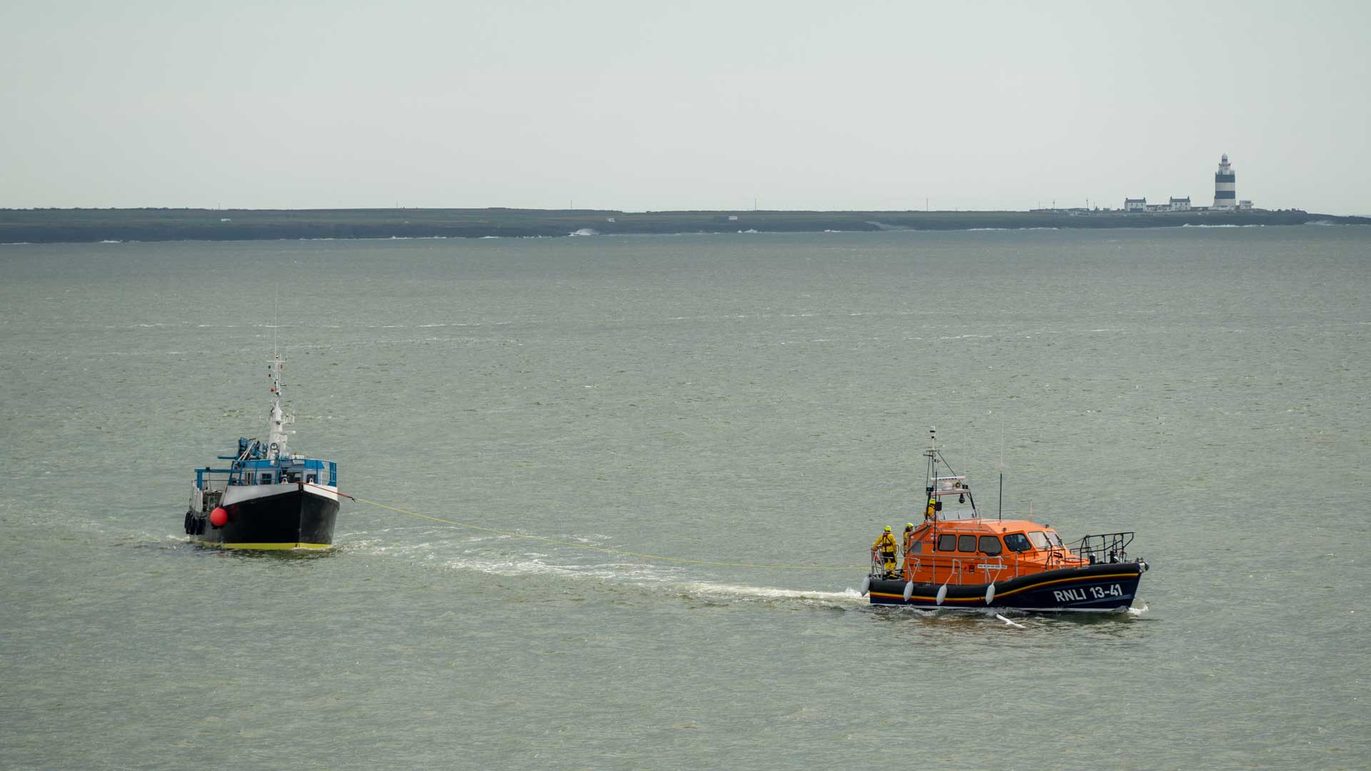 Picture of fishing boat being towed with Hook Head lighthouse in the background