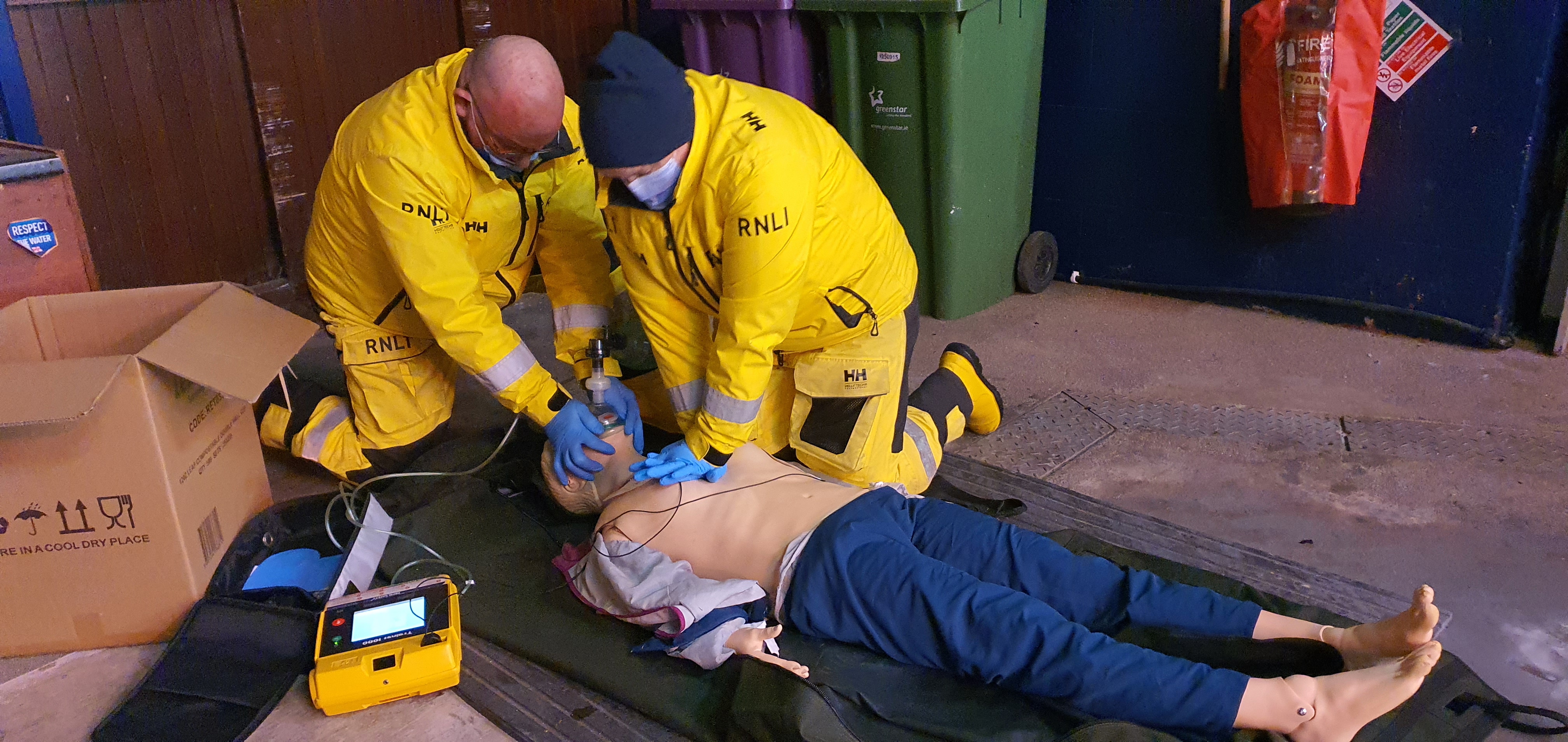 Two volunteers training with a manequin for CPR