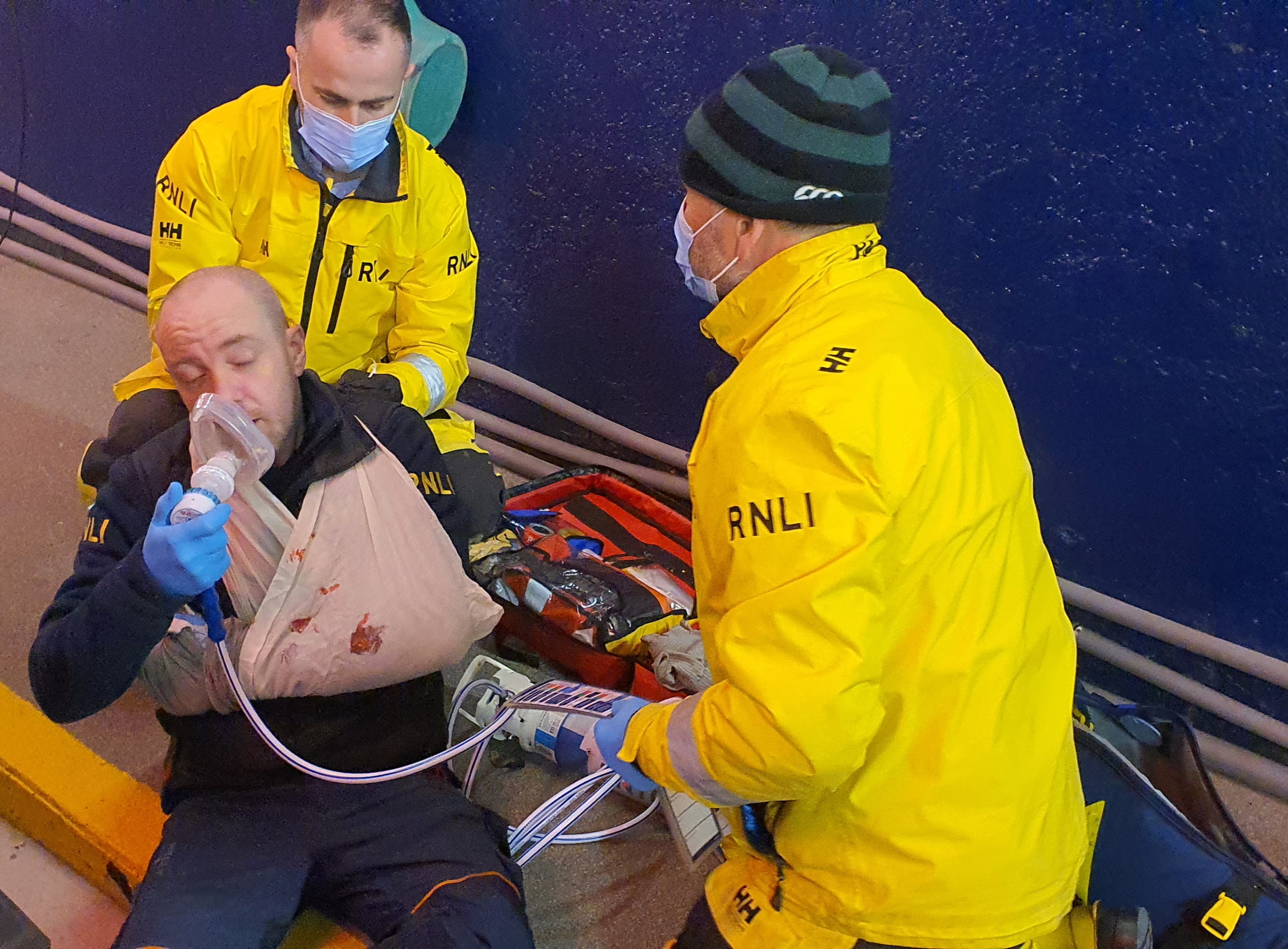 Two volunteers tend to a person with an injured hand