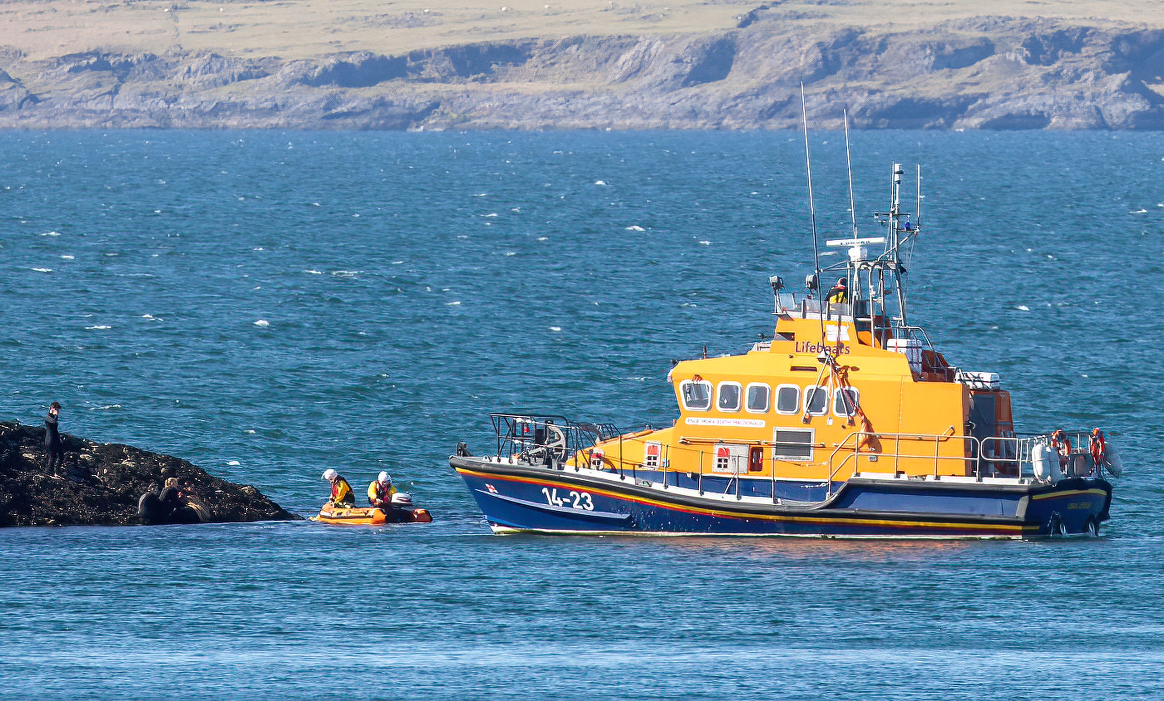 The Oban lifeboat sits off Maiden Island with two crew on an inflatable daughter craft crossing the short distance to the casualty on the shore