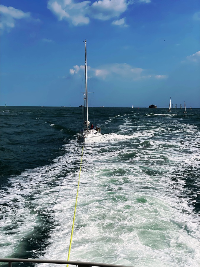 Yacht under tow at the entrance to Portsmouth Harbour