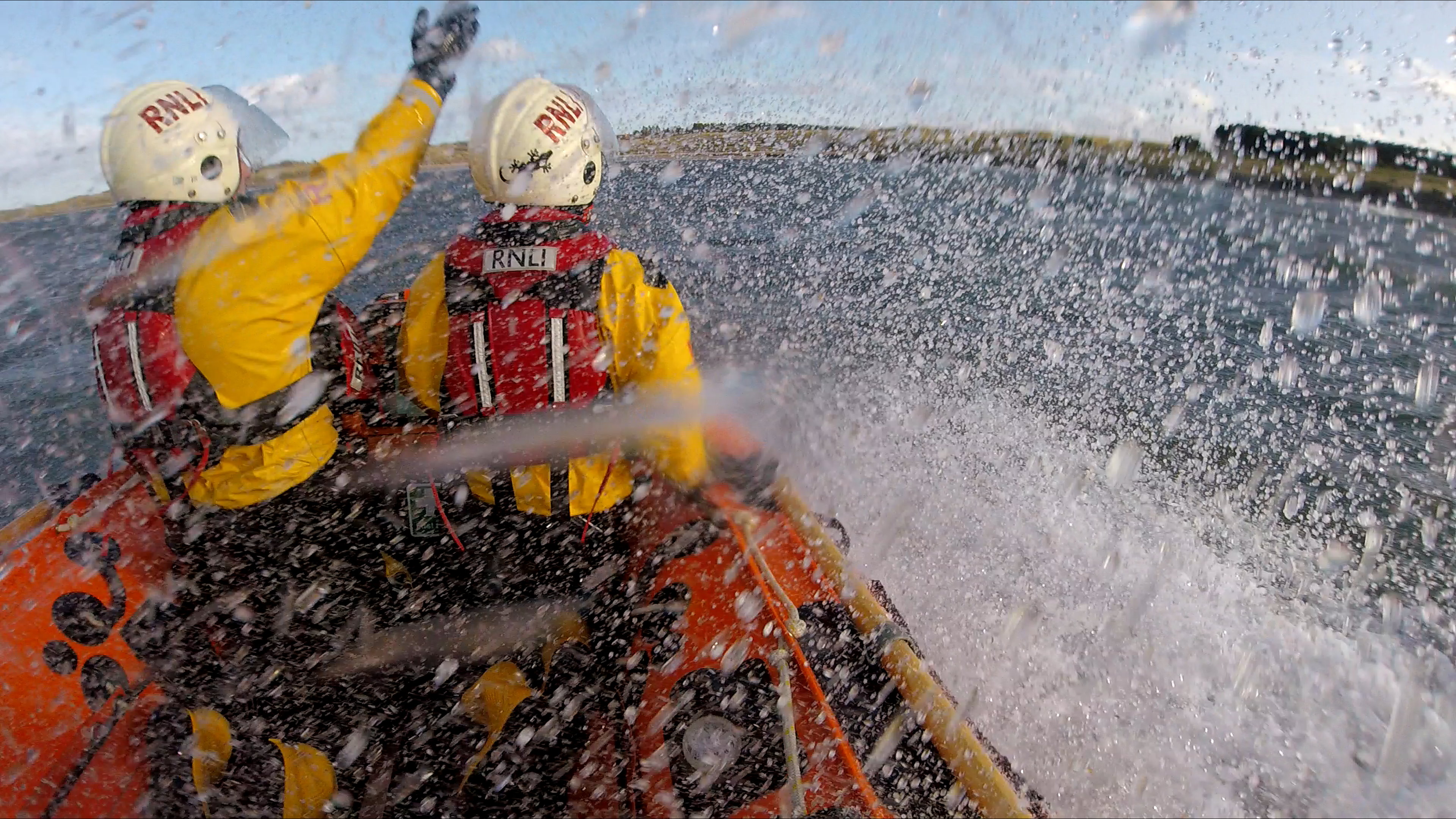 North Berwick RNLI crew members at the front of the lifeboat, viewed from the back with a crew member pointing towards the casualty