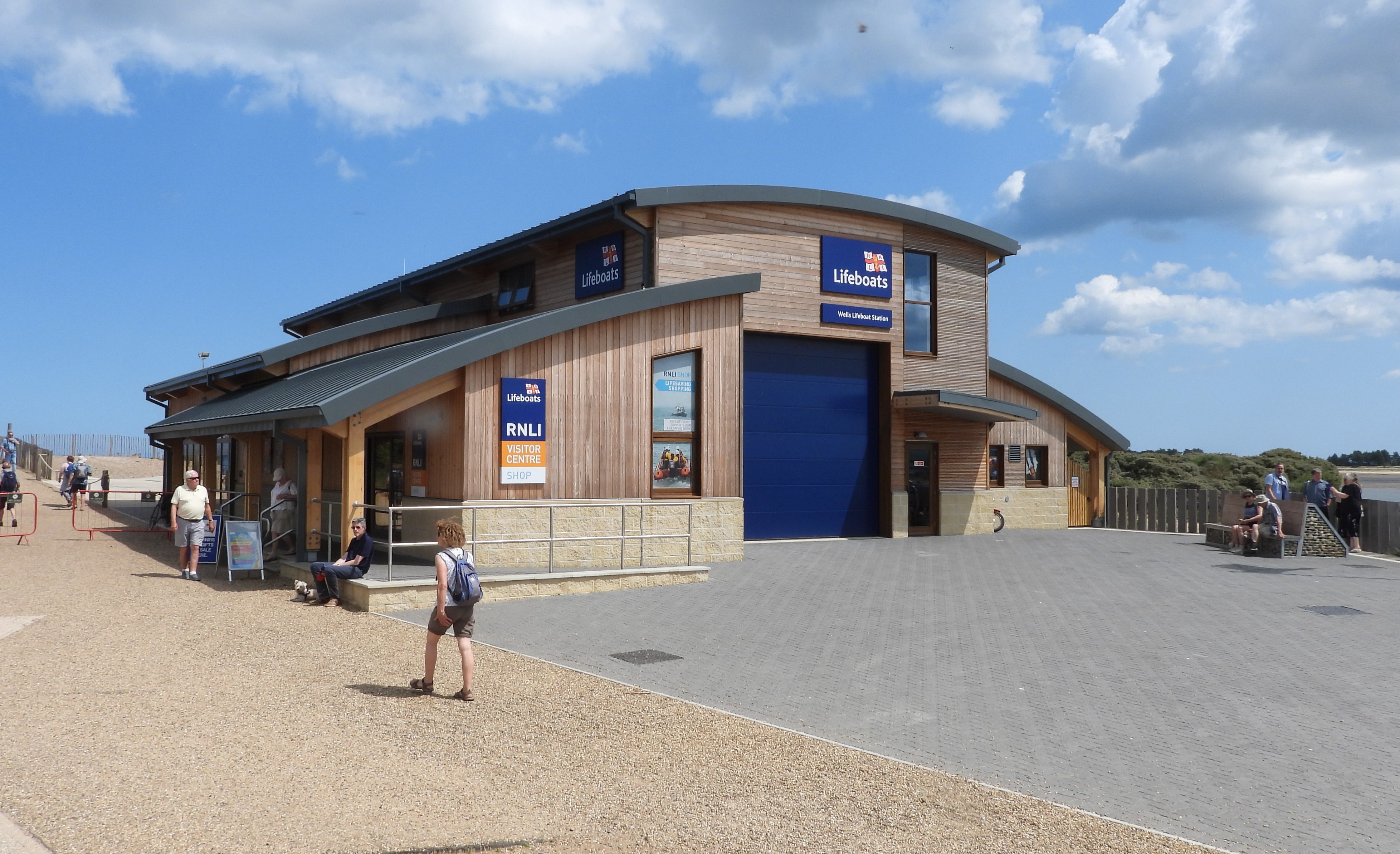 Photo of the Wells RNLI new boathouse with blue sky and people walking past
