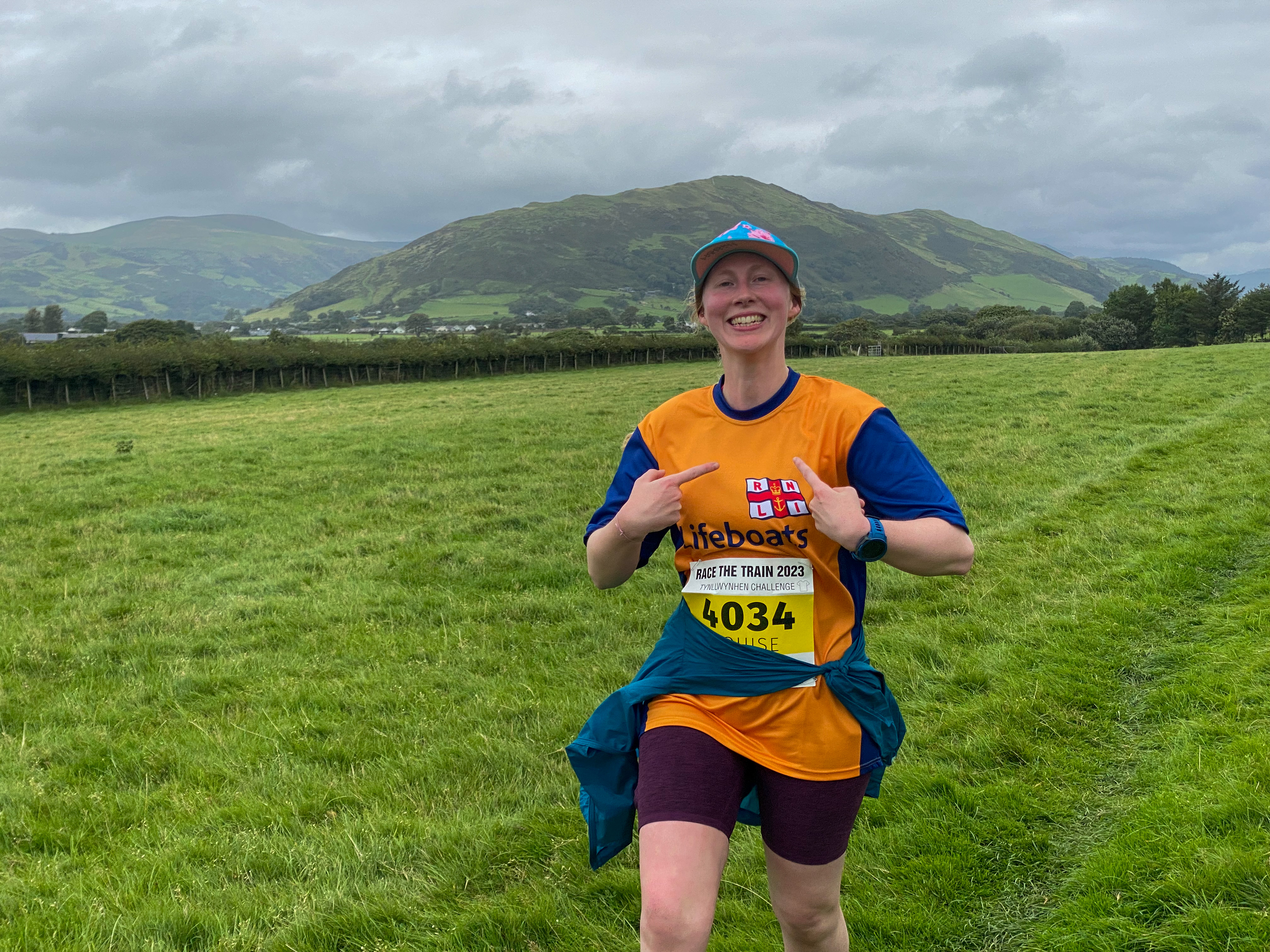 Louise running across a field with Welsh hills behind