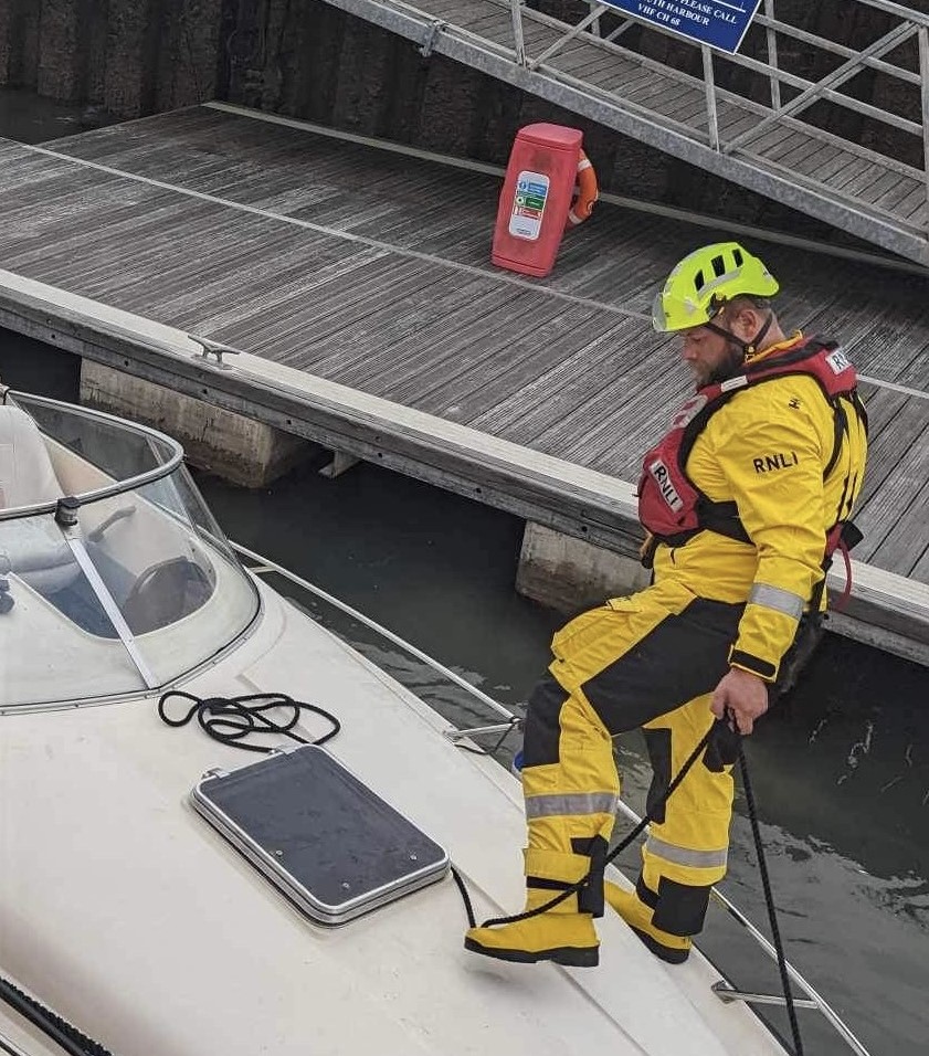 Photo showing crew member Tom on the deck of the motor boat assisting with the alongside tow in Yarmouth Harbour.
