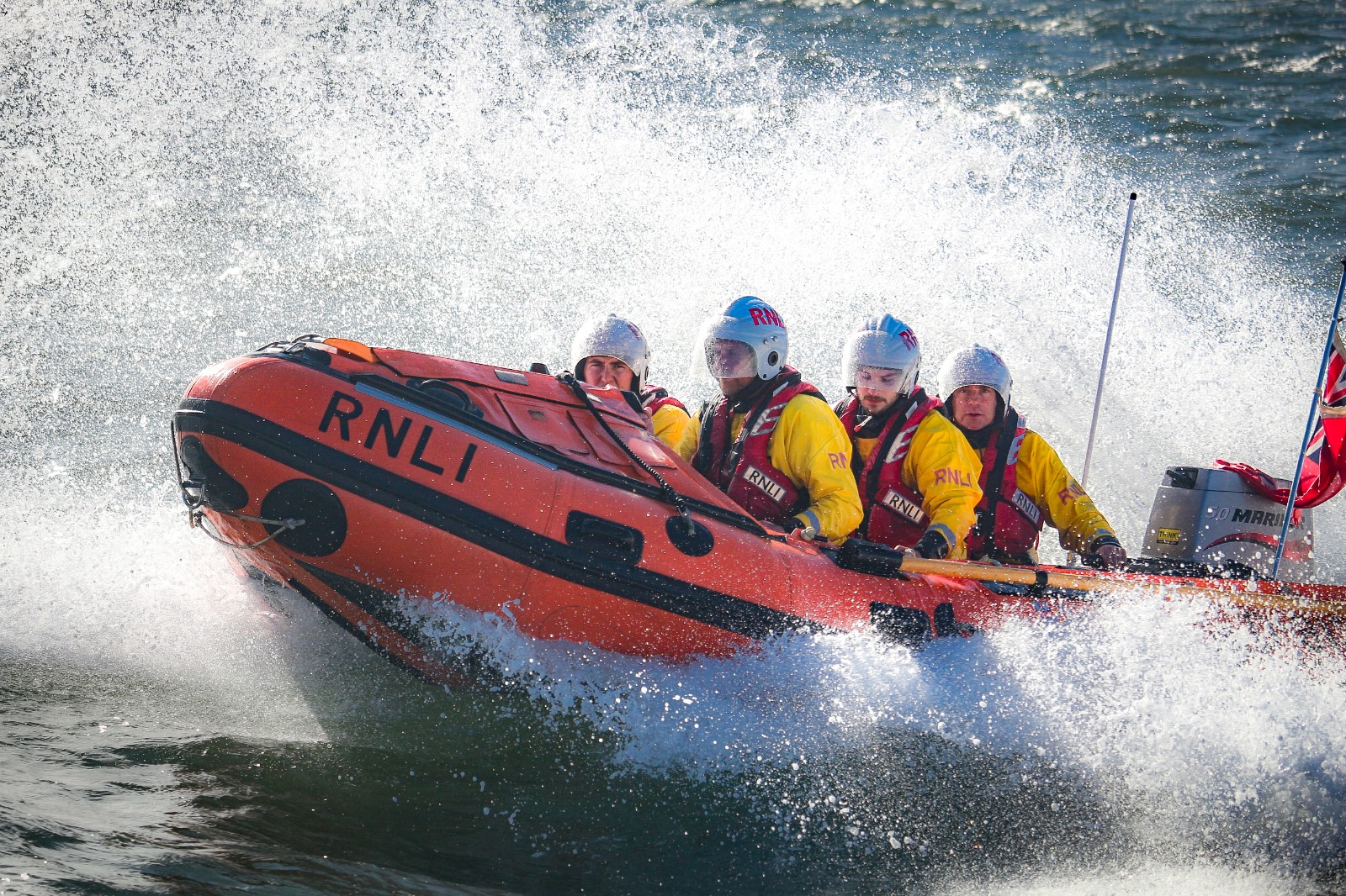 The D-Class lifeboat at sea with spray over the side of the lifeboat with 4 crew members