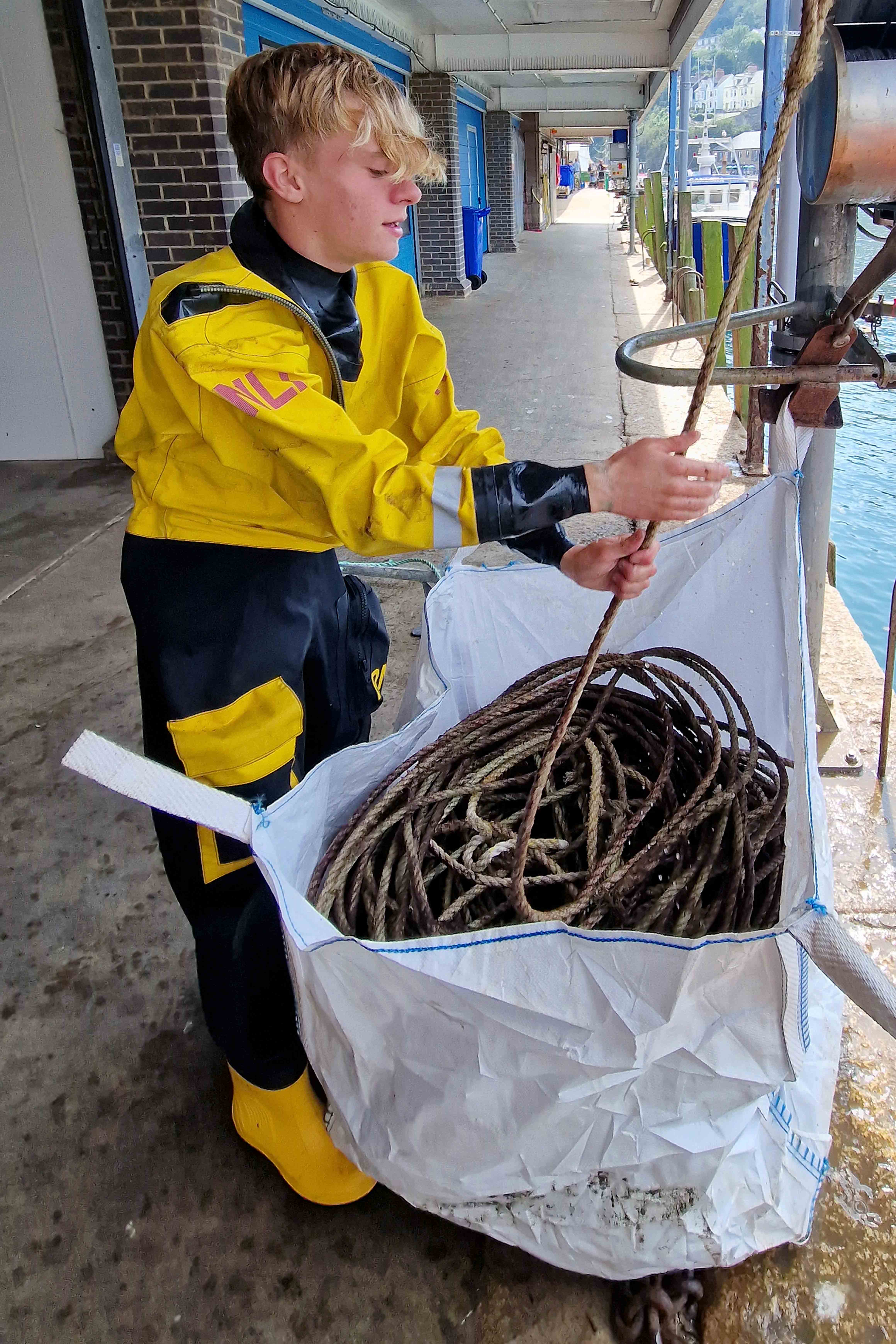 Looe RNLI volunteer crew Will Jaycock unloading the rope onto East Looe Quay