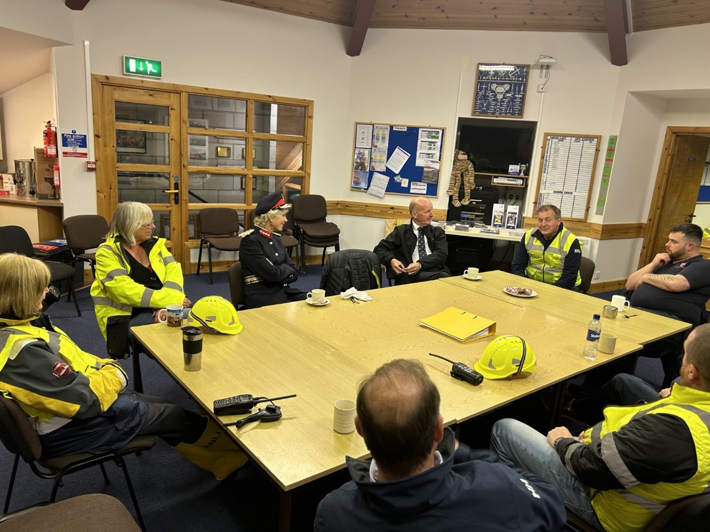 The Lord Lieutenant and lifeboat crew in the station sat around a table with tea and biscuits