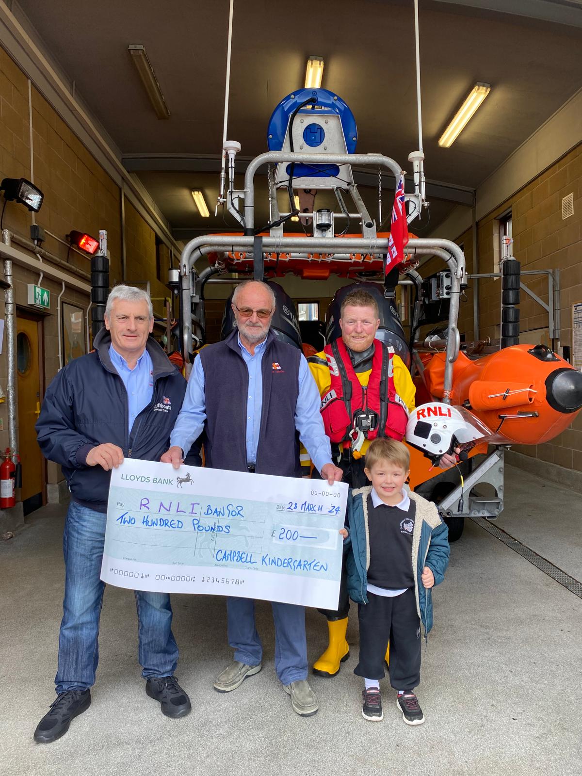 Bangor RNLI volunteers John Montgomery, John Magowan and Chris Beale receiving a cheque from Henry Scott