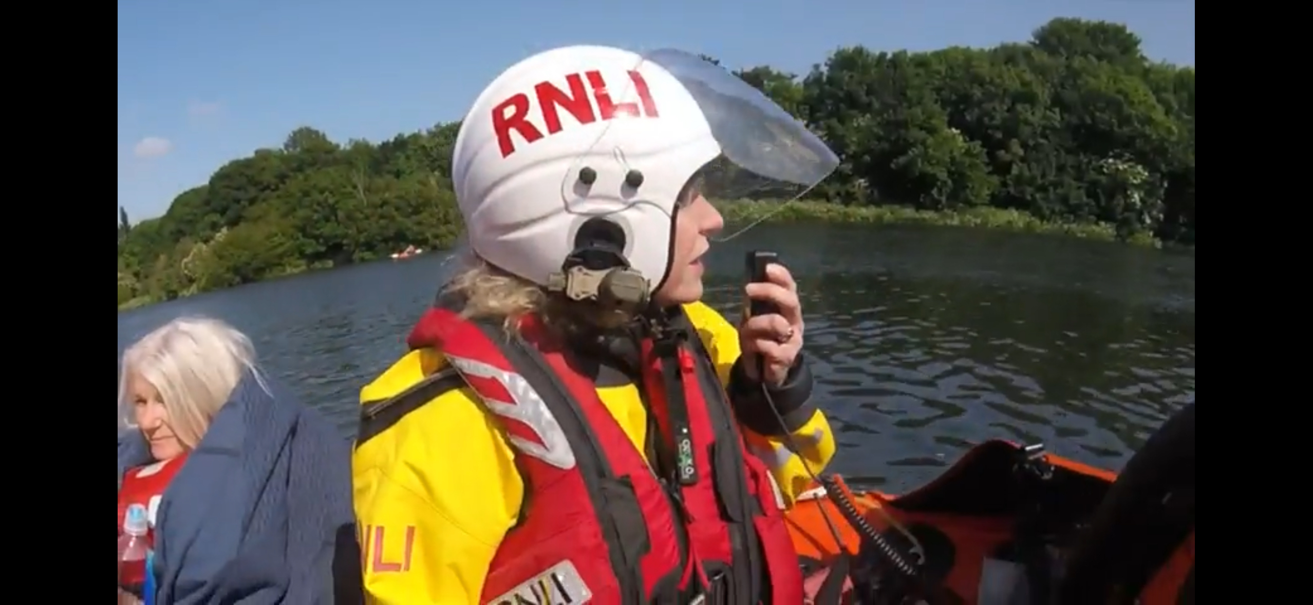 Female crew member communicates on radio with lady casualty in lifeboat