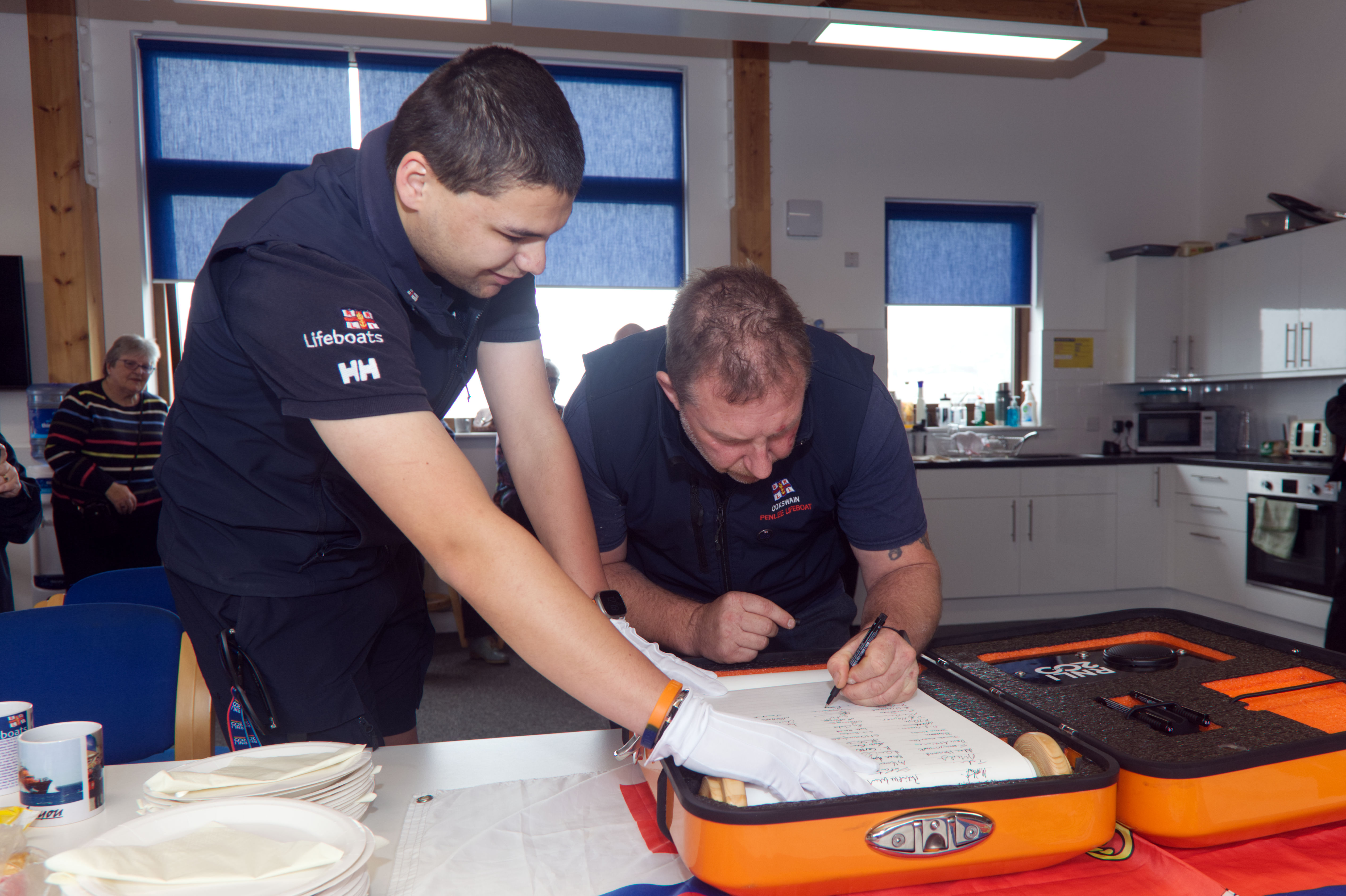 Picture shows coxswain signing the scroll