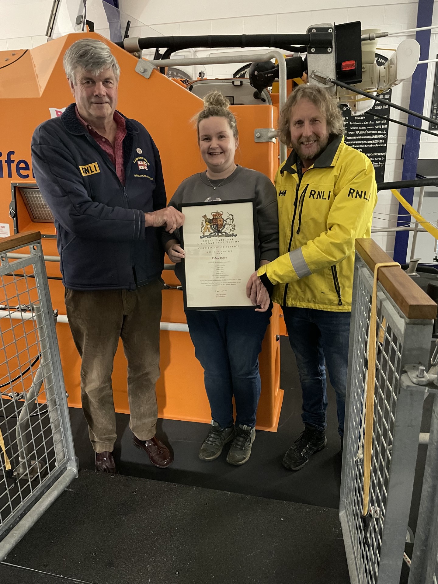 Presenting her Certificate of Service to Kelsey are Lifeboat Operations Manager Captain Marcus Elliott (left) and Coxswain Graham Heritage (right).