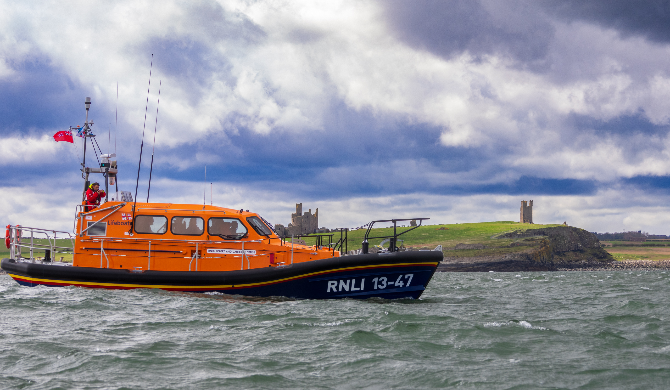Side shot of Lifeboat 13-47 passing East of Dunstanburgh Castle