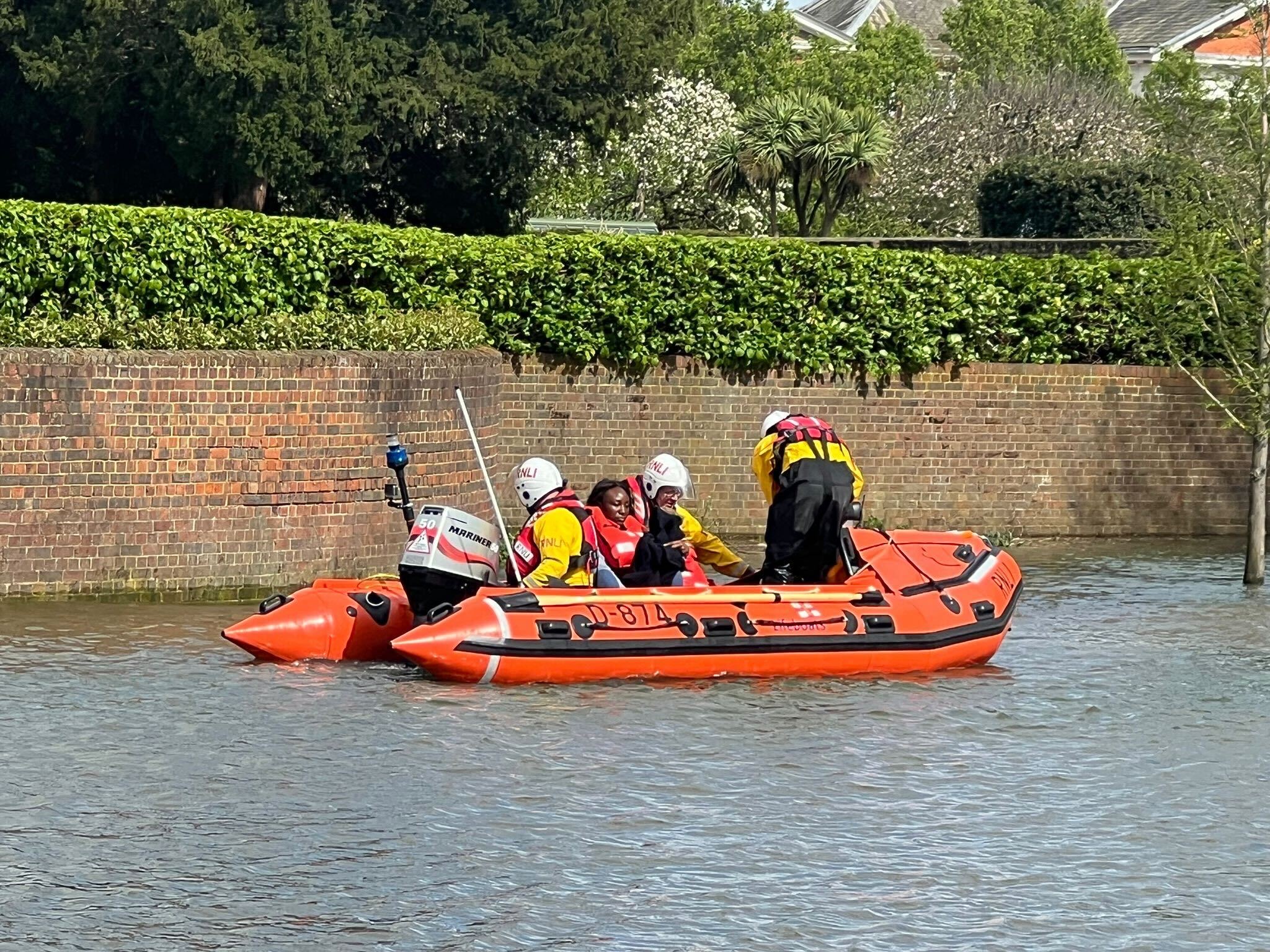 Lifeboat with two casualties on board near high brick wall.
