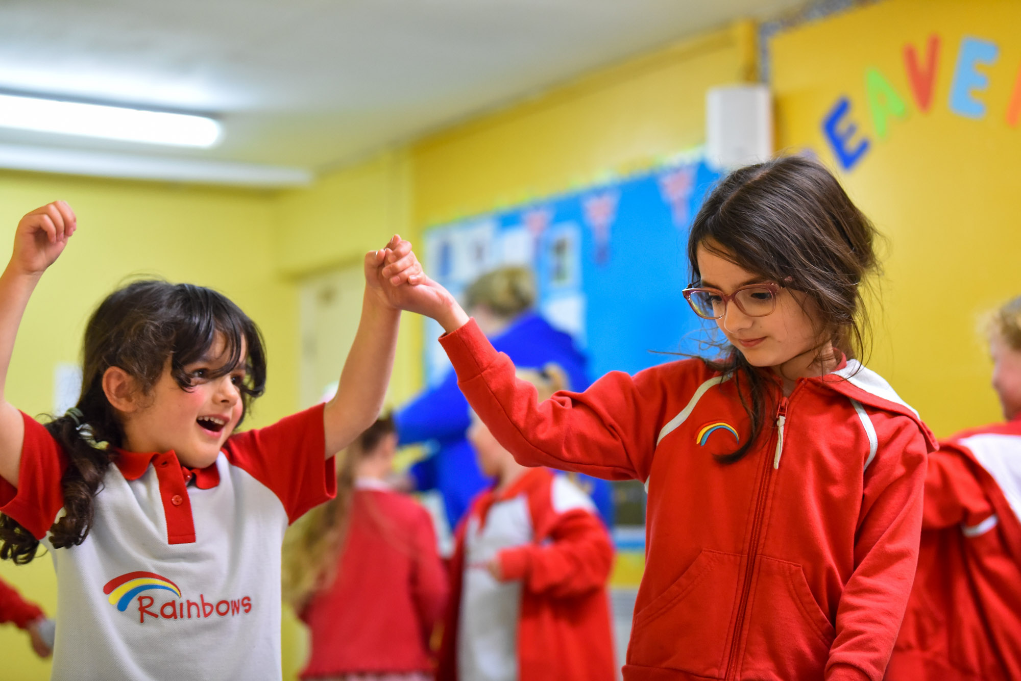 Two young girls in red uniform, holding each others hands in the air.