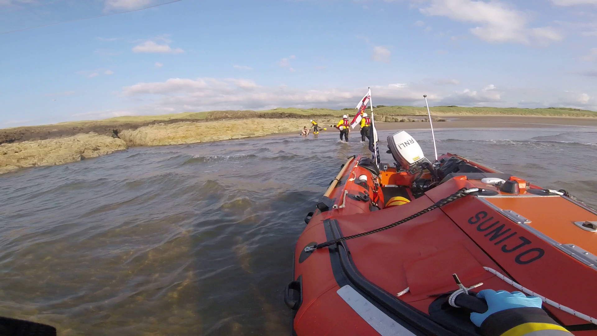 North Berwick RNLI head ashore to assist casualty viewed from the shallows as crew member holds the lifeboat