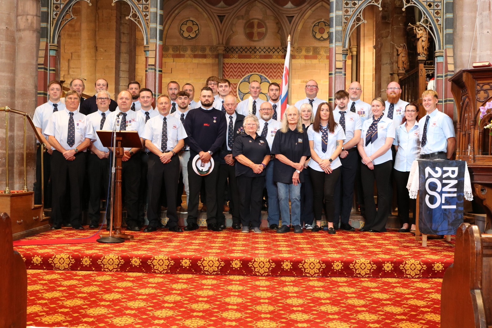 Volunteers crew and fundraisers posing for a group photo in front of the altar in St Bees Priory

