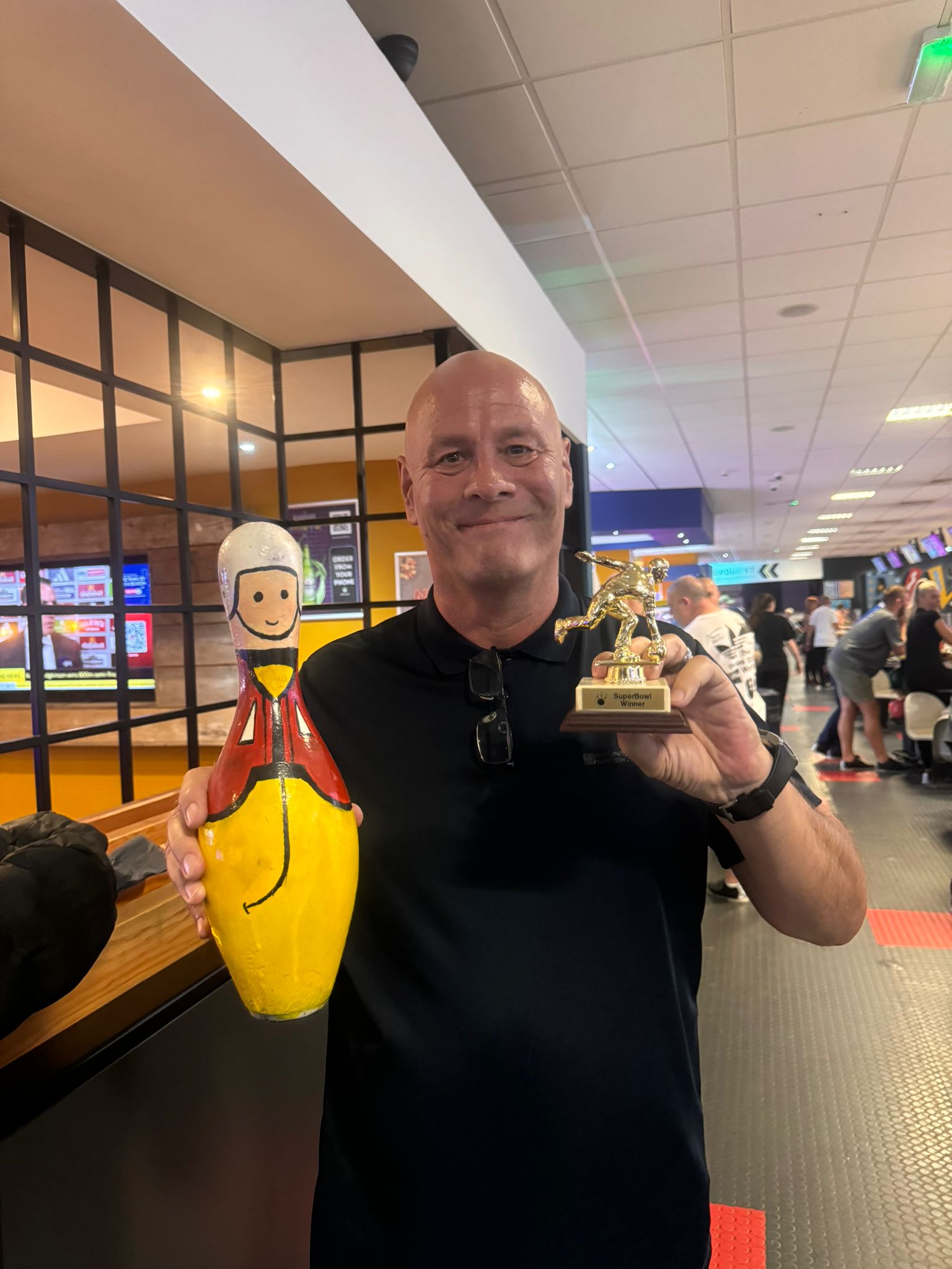 Volunteer LA, Mark, poses with his bowling trophies won on the night. 