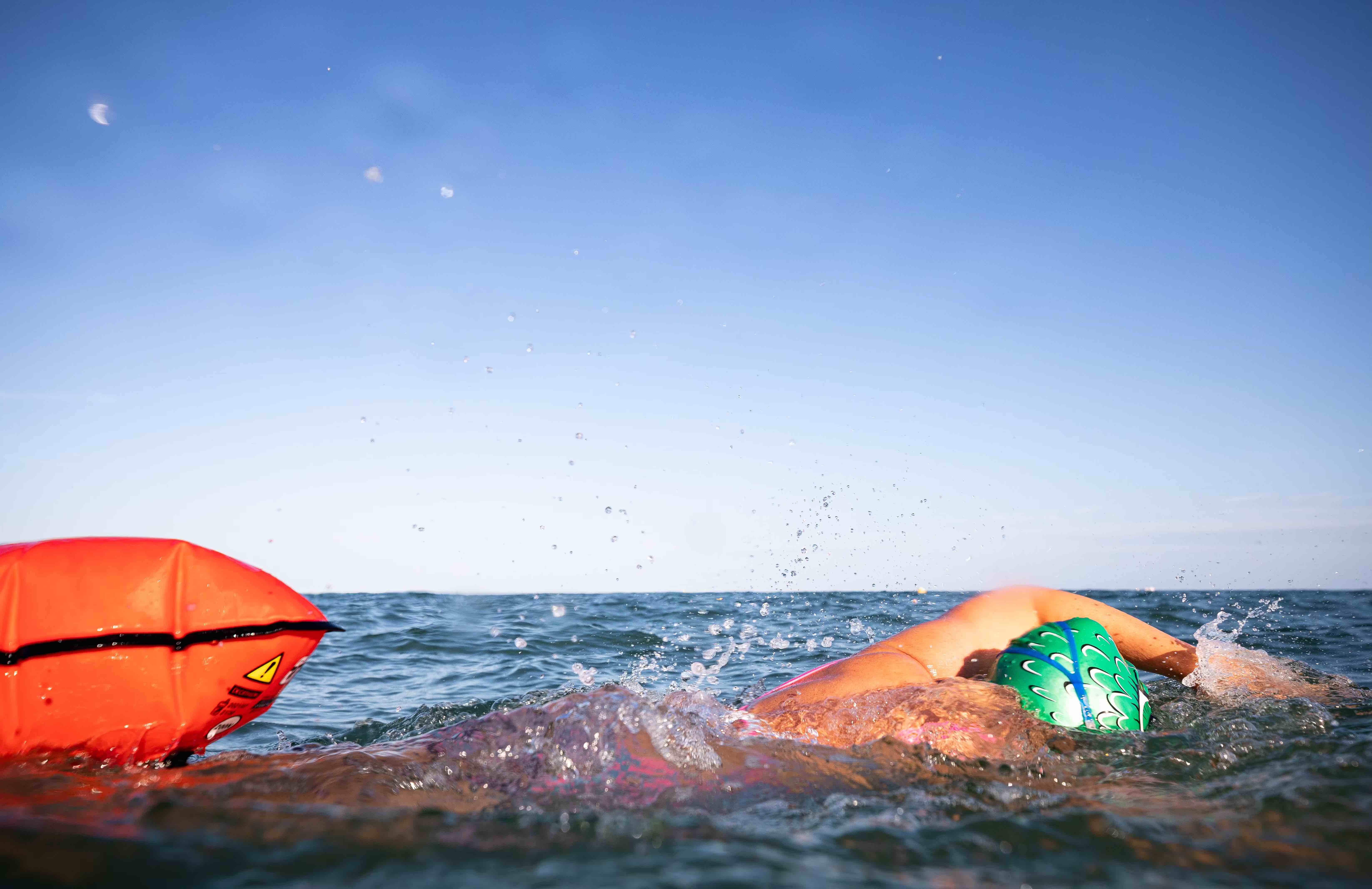 Open-water swimmer with towing float &amp; brightly coloured swim hat