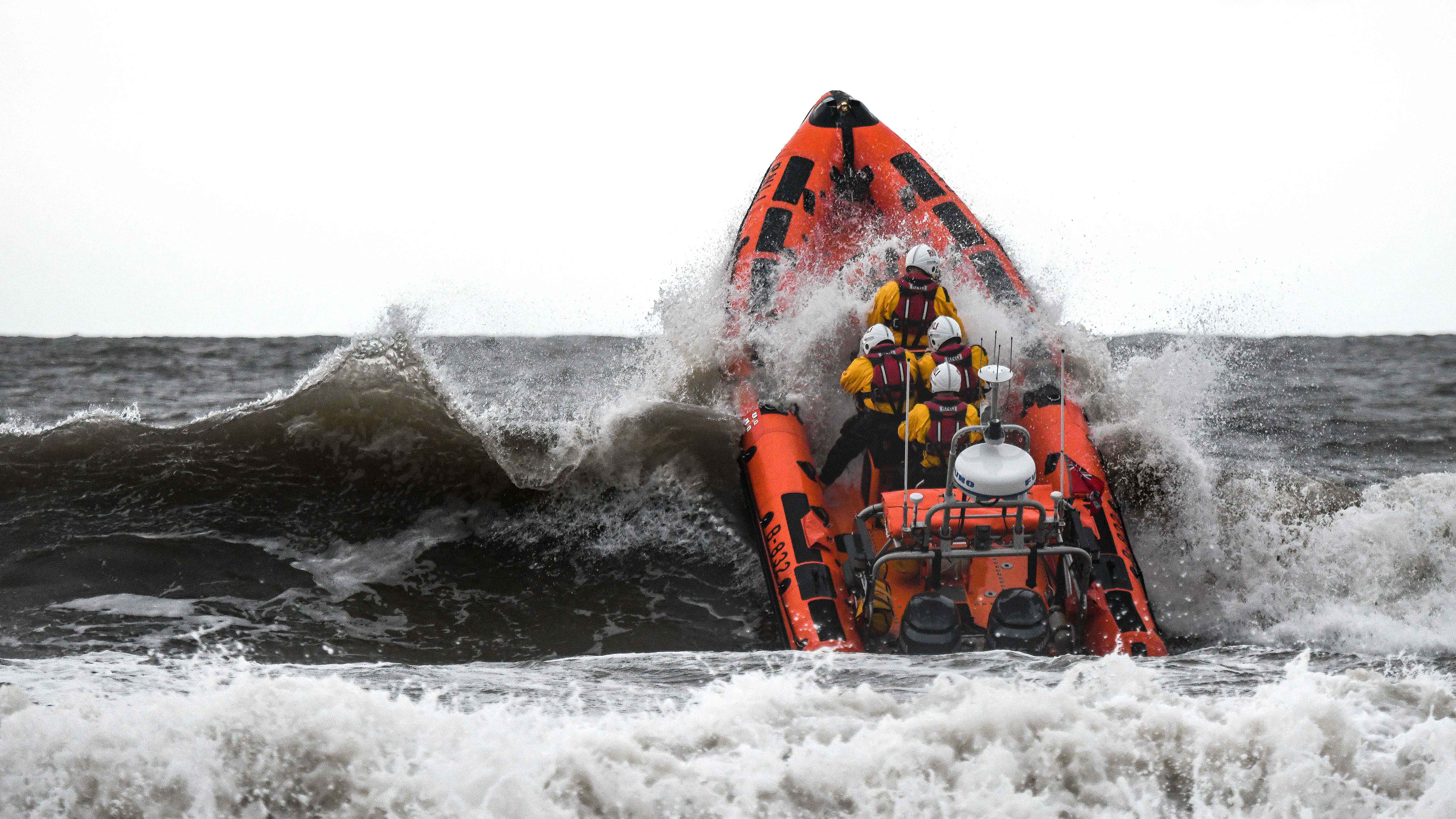 RNLI Atlantic 85 lifeboat punching through waves in stormy conditions.