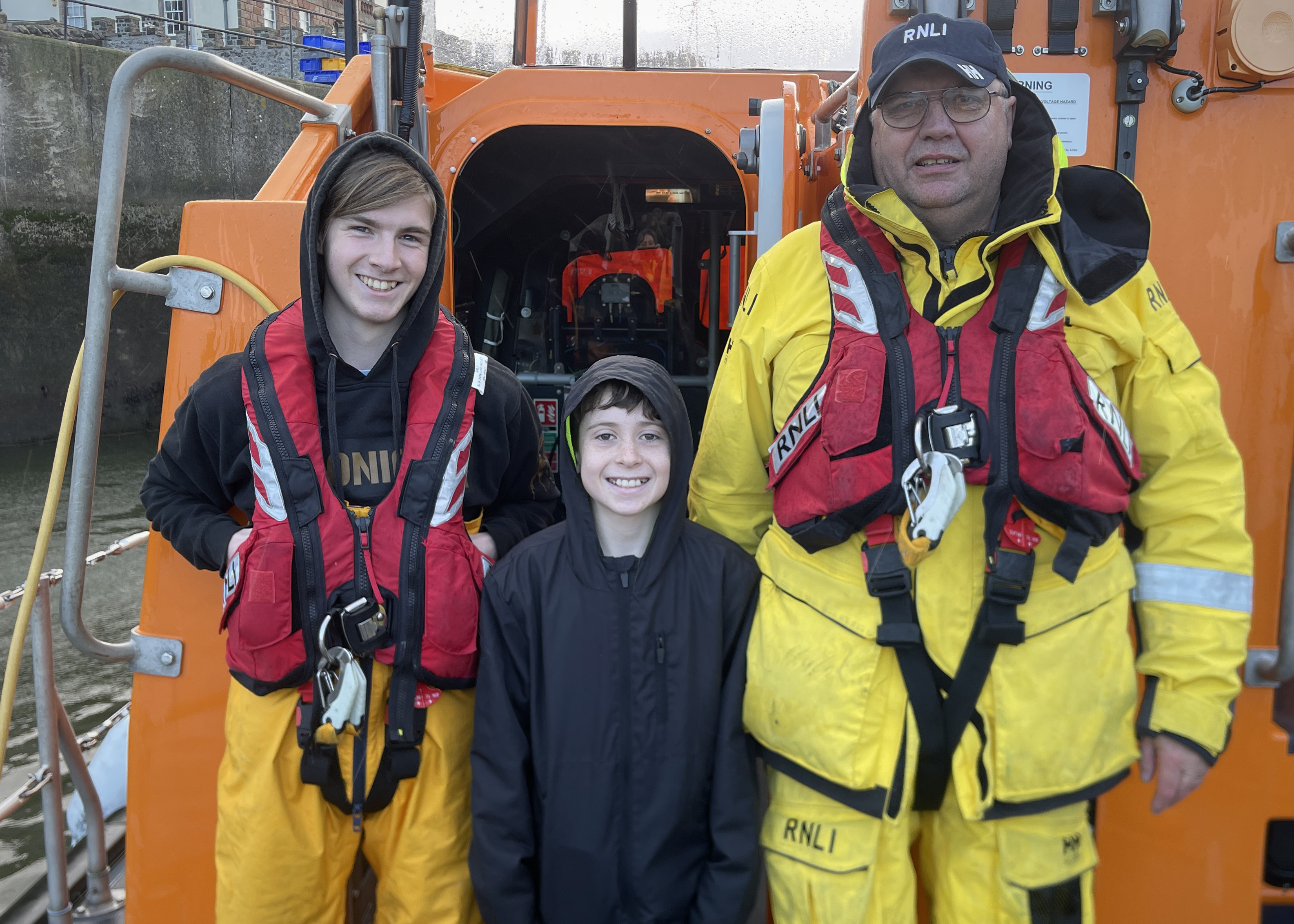 Haydn Sword, age 11, from Eyemouth visits Eyemouth RNLI lifeboat during his Reindeer Run Challenge 2024. Haydn is pictured on the lifeboat with two crew members.