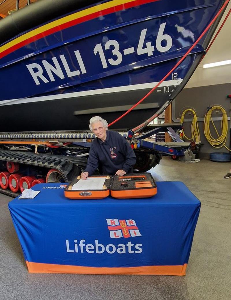 Sheila Warner MBE signing 200th anniversary RNLI scroll in front of Wells RNLI’s Shannon class lifeboat ‘Duke of Edinburgh’
