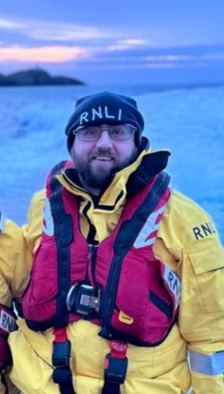 Cedwyn, Volunteer Lifeboat Press Officer and trainee crew member on return from exercise on the charity’s all weather Trent class lifeboat Blue Peter VII on a January evening, sun setting in the background behind Strumble Head Lighthouse.