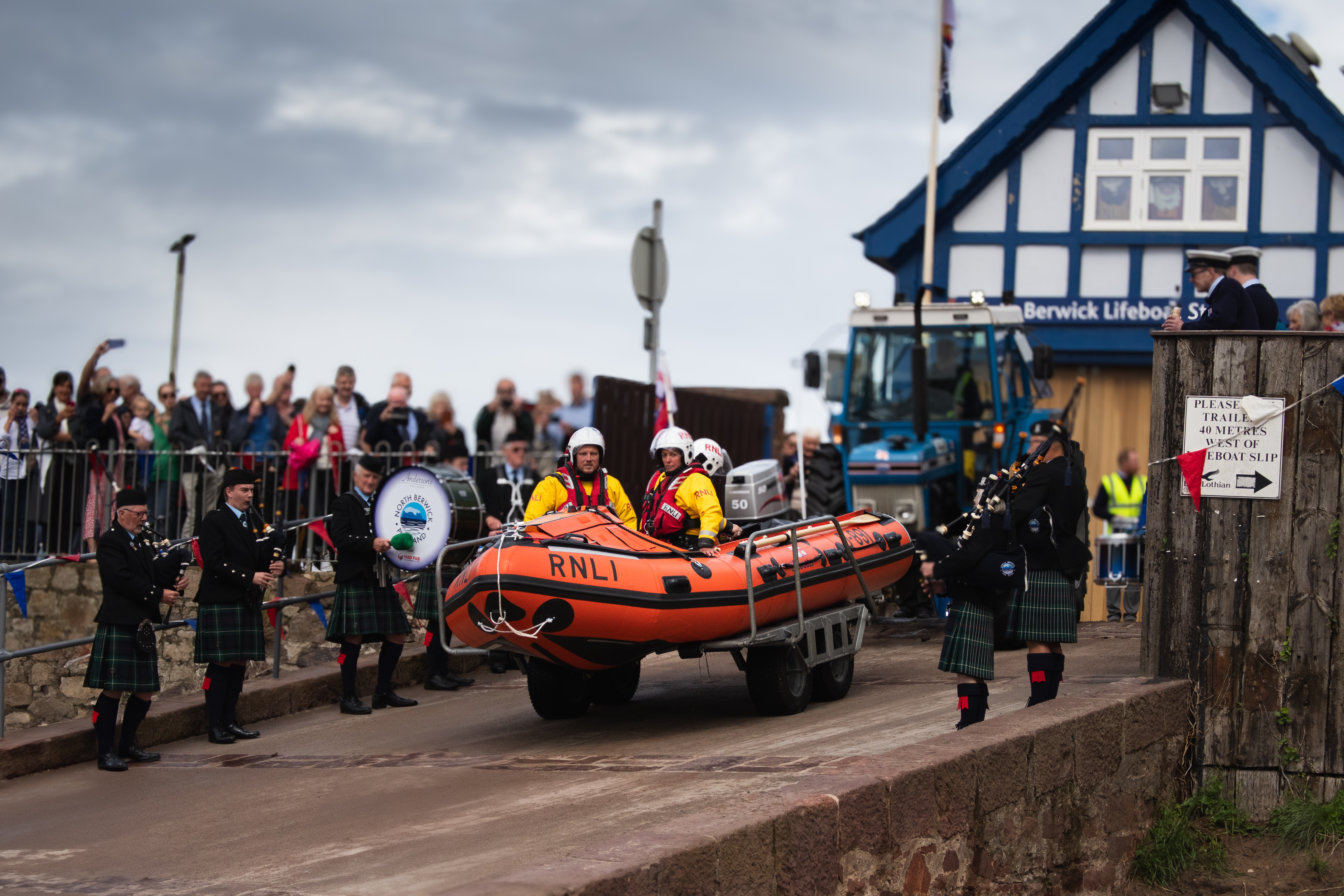 Lifeboat descends slipway with pipe band flanking either side