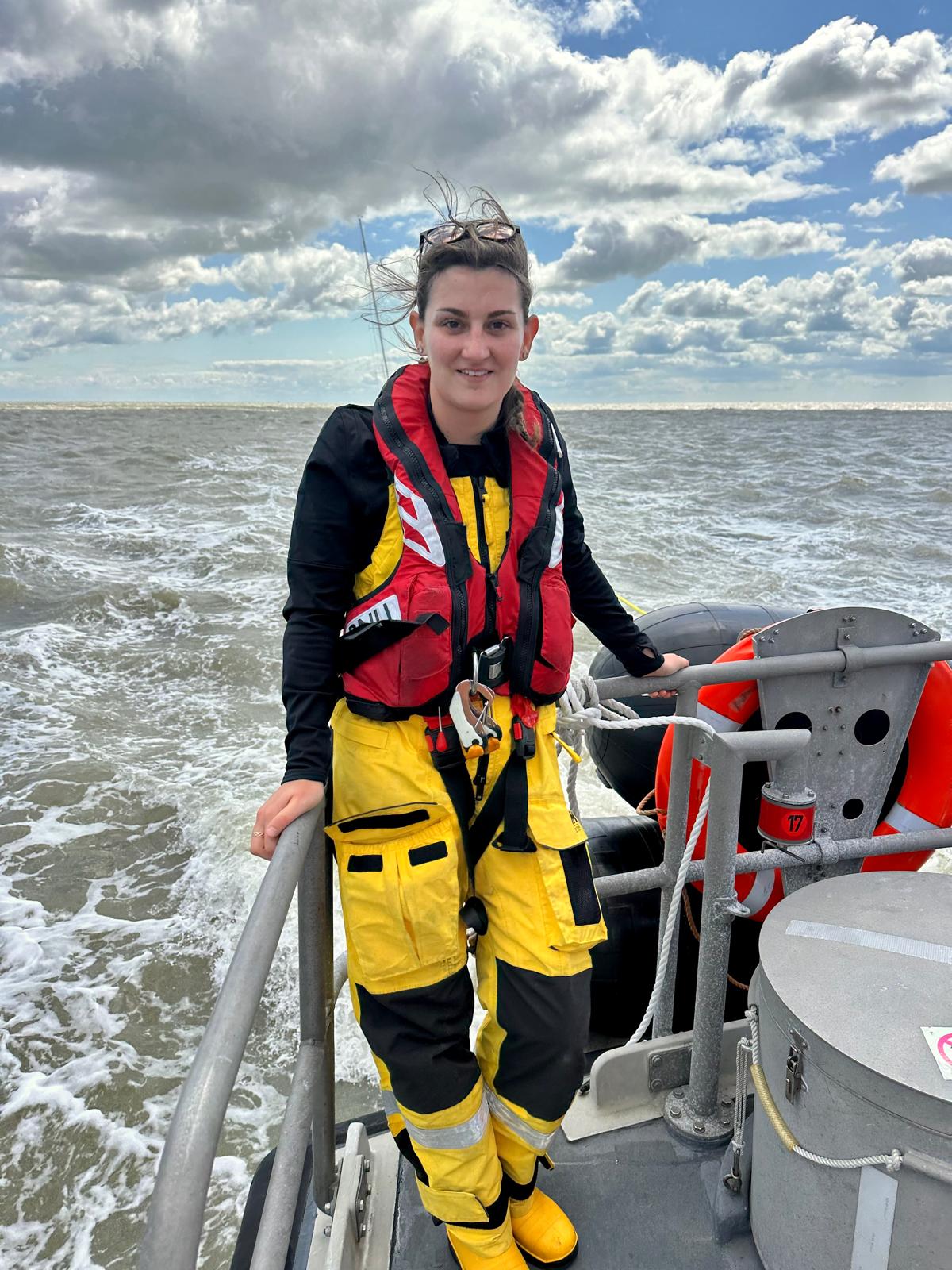 A female RNLI crew standing on a lifeboat at sea